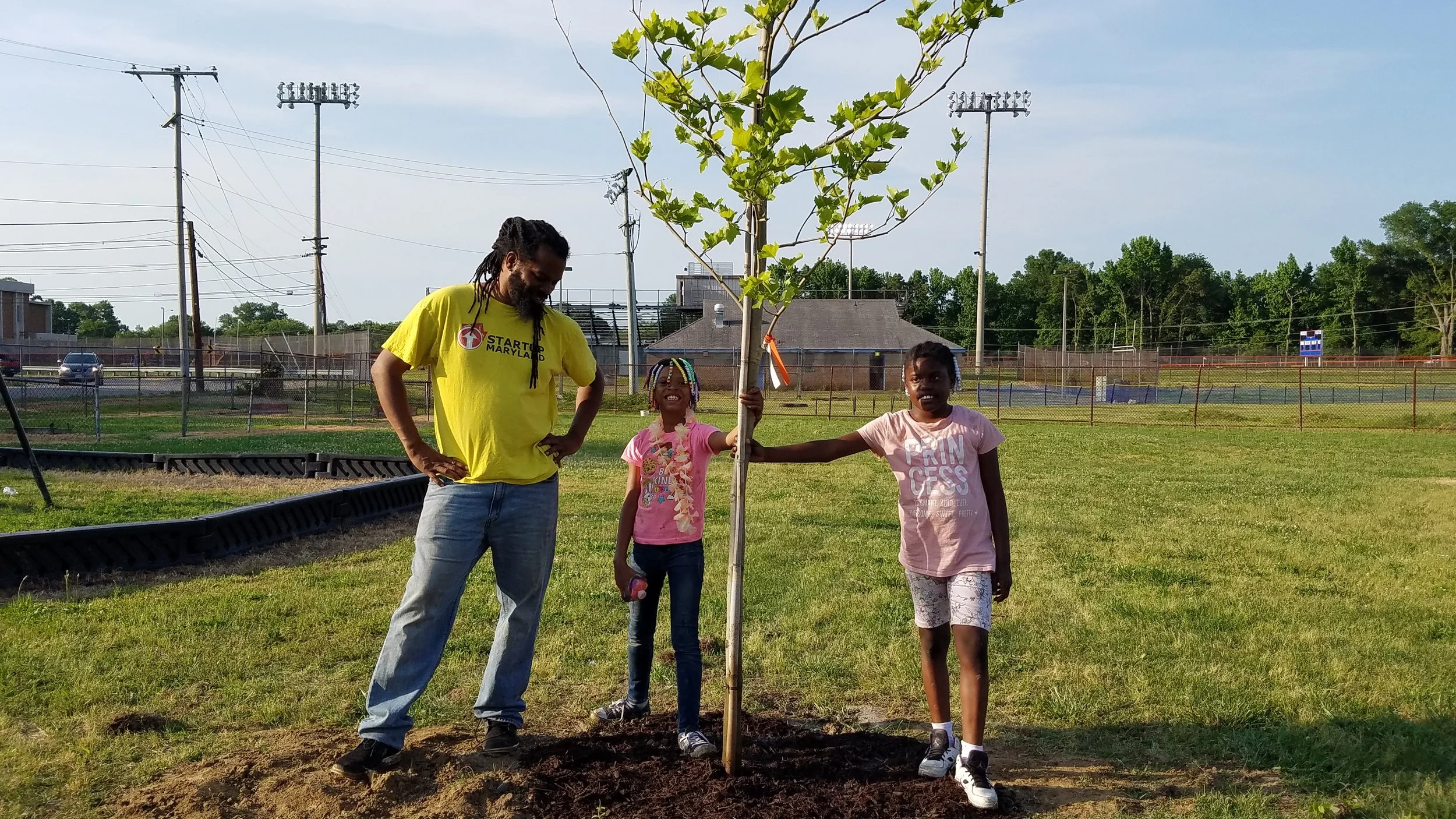 Duron Chavis stands with two proud members after they planted their first tree.