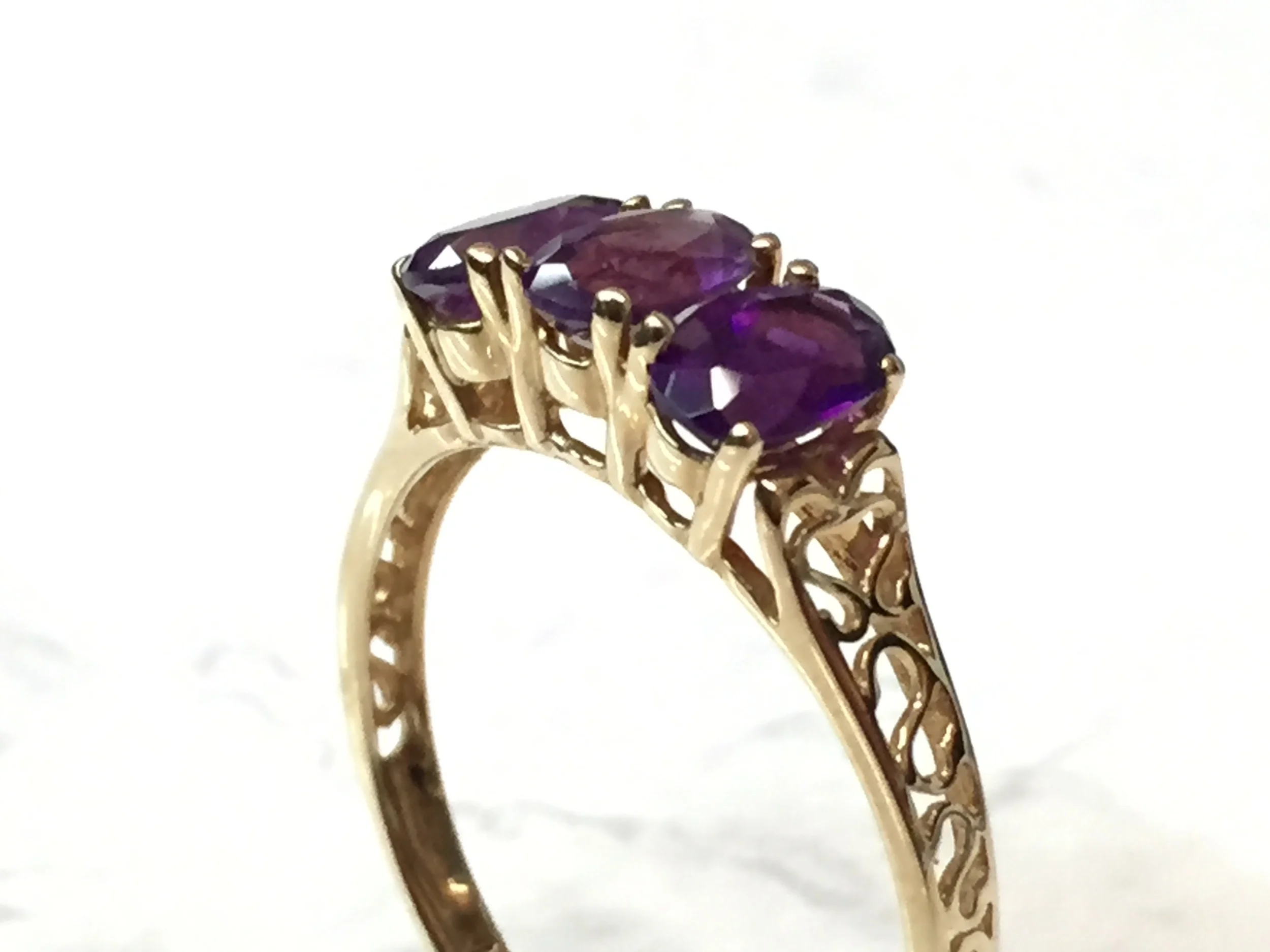 Three-stone amethyst ring in 10K yellow gold with decorative filigree, on sale for $150.00