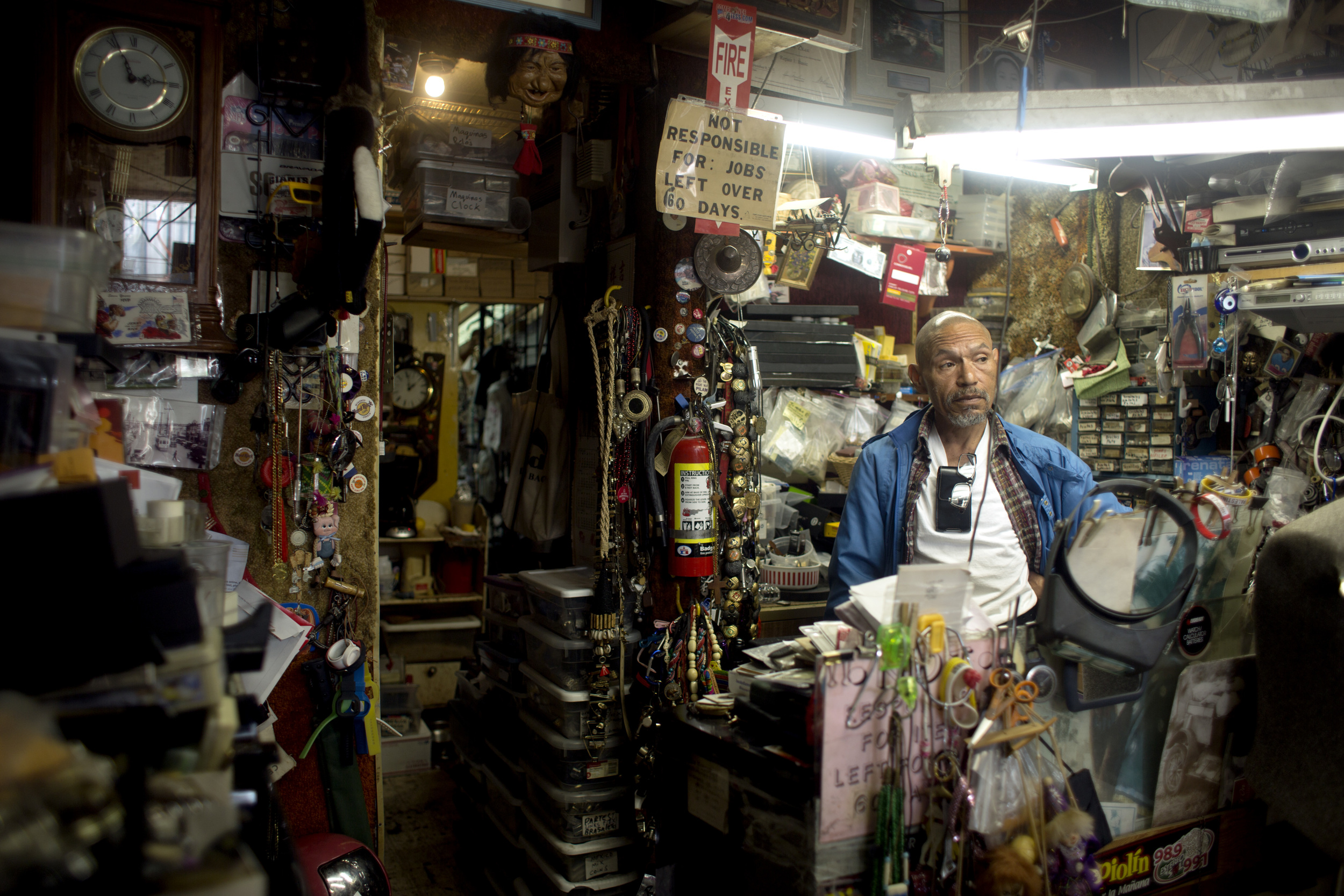 Nelson Diaz, owner of Tony's Watch and Jewelry Repair store on the corner of Geneva Ave. and Mission Street looks at customers waiting for their repairs in San Francisco, Calif. Monday June 15, 2015.