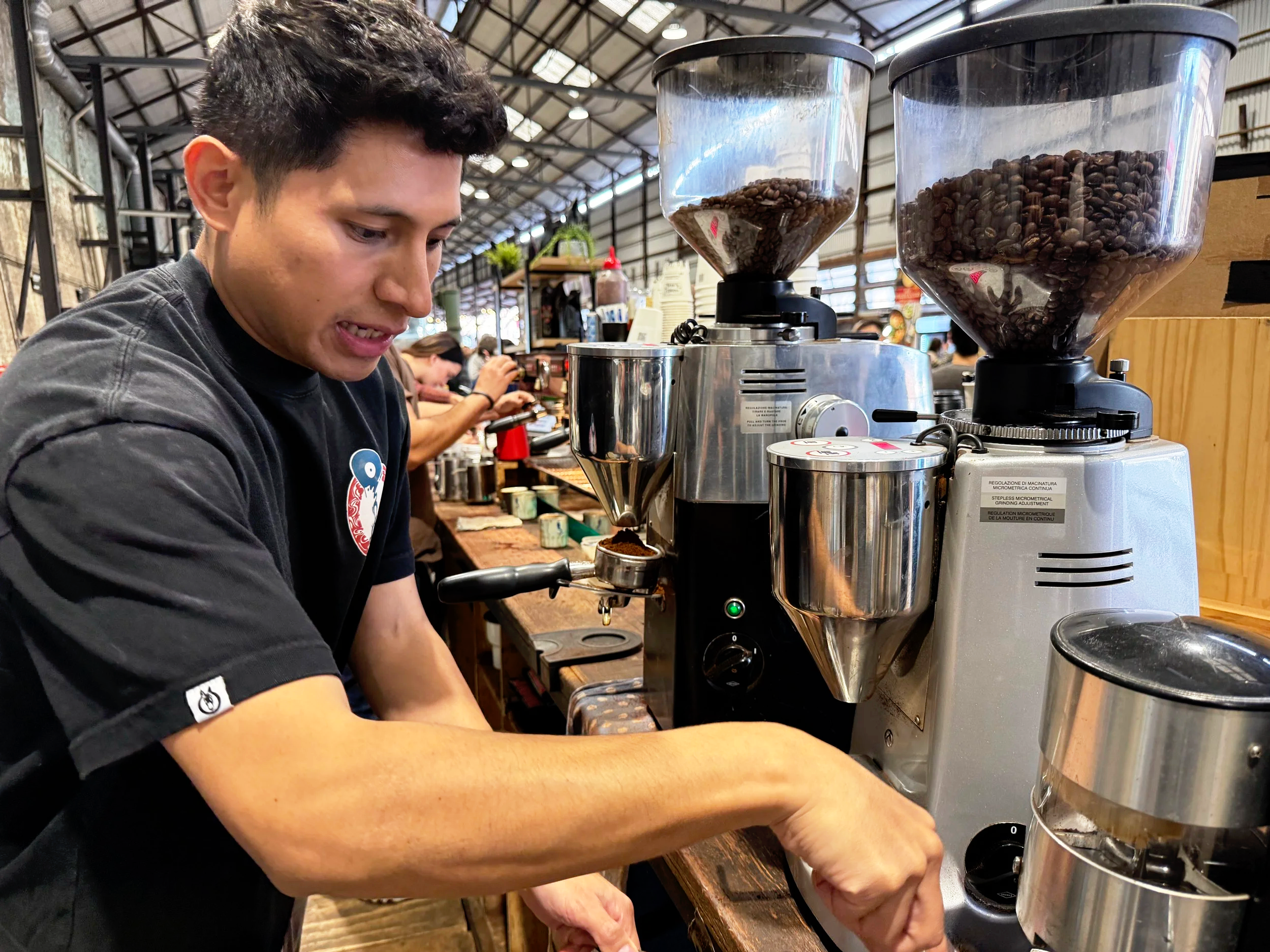 A Mule Coffee Roasters barista grinding freshly roasted coffee beans for espresso service at Carriageworks Markets.