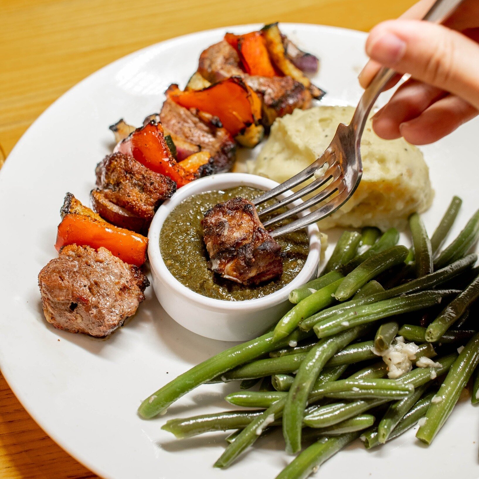 Feast your eyes (and forks) on our Filet Kabob! Tender skewered tenderloin, grilled to perfection with a colorful medley of zucchini, red onion, and red pepper. Served alongside our beloved garlic mashed potatoes and tender green beans. Wood-fired pe