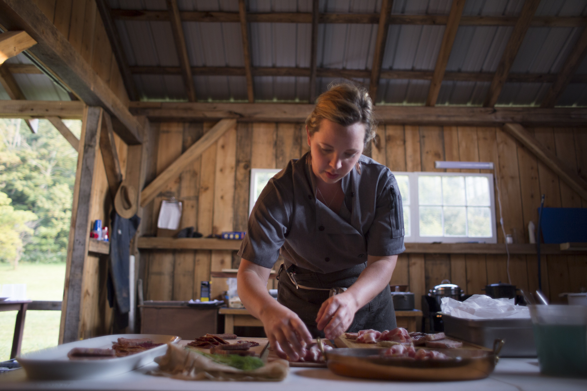 Becky Clark, chef-butcher and owner of Pork and Pickles, prepares a dish during a benefit dinner for Community Food Initiatives at Homecoming Farm in Amesville, Oh. 