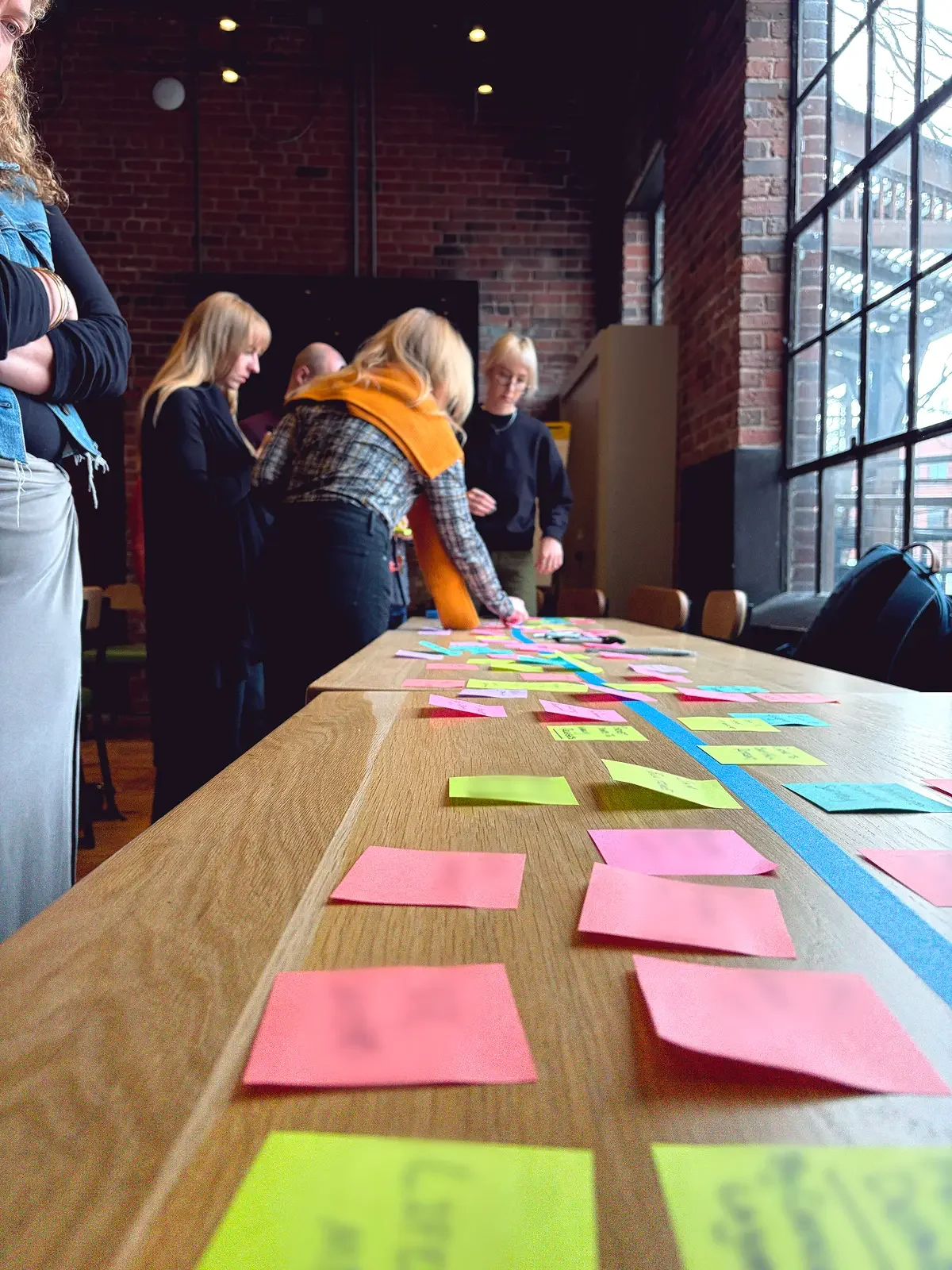 A group of people collaborating on a brainstorm with sticky notes during a Work Design workshop.