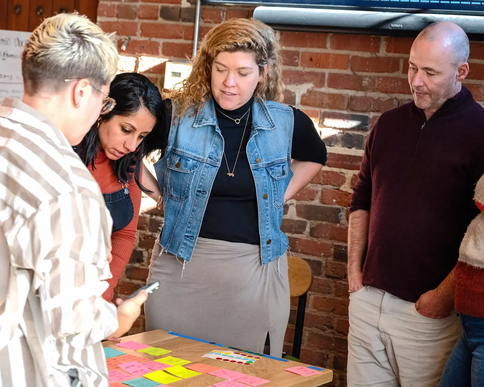A small group of three people huddles around a table during a The Ready workshop.