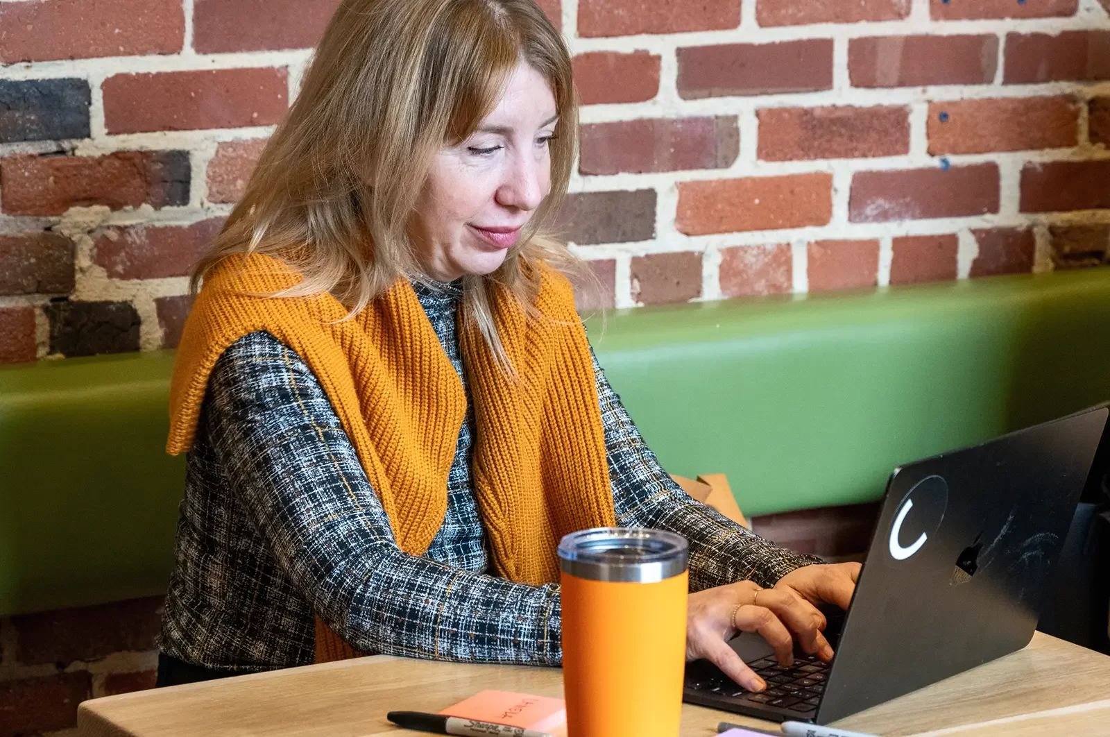 A woman working on a laptop at a table, representing focused independent work.