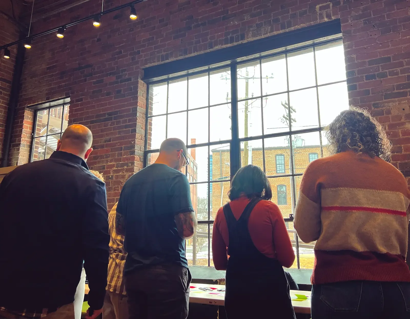A group of leaders viewed from behind, gathered at a window during a The Ready offsite workshop.