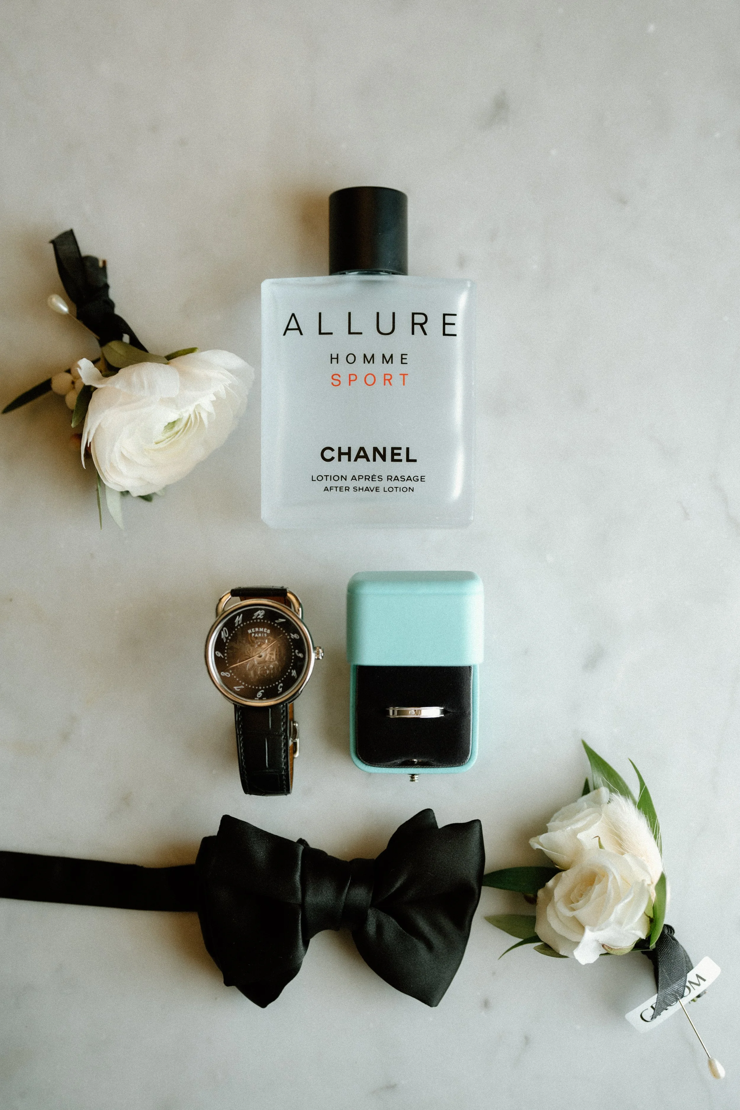Groom details include Tiffany & Co. wedding band, Hermes watch, Chanel after shave, black bow tie and white ranunculus boutonniere 