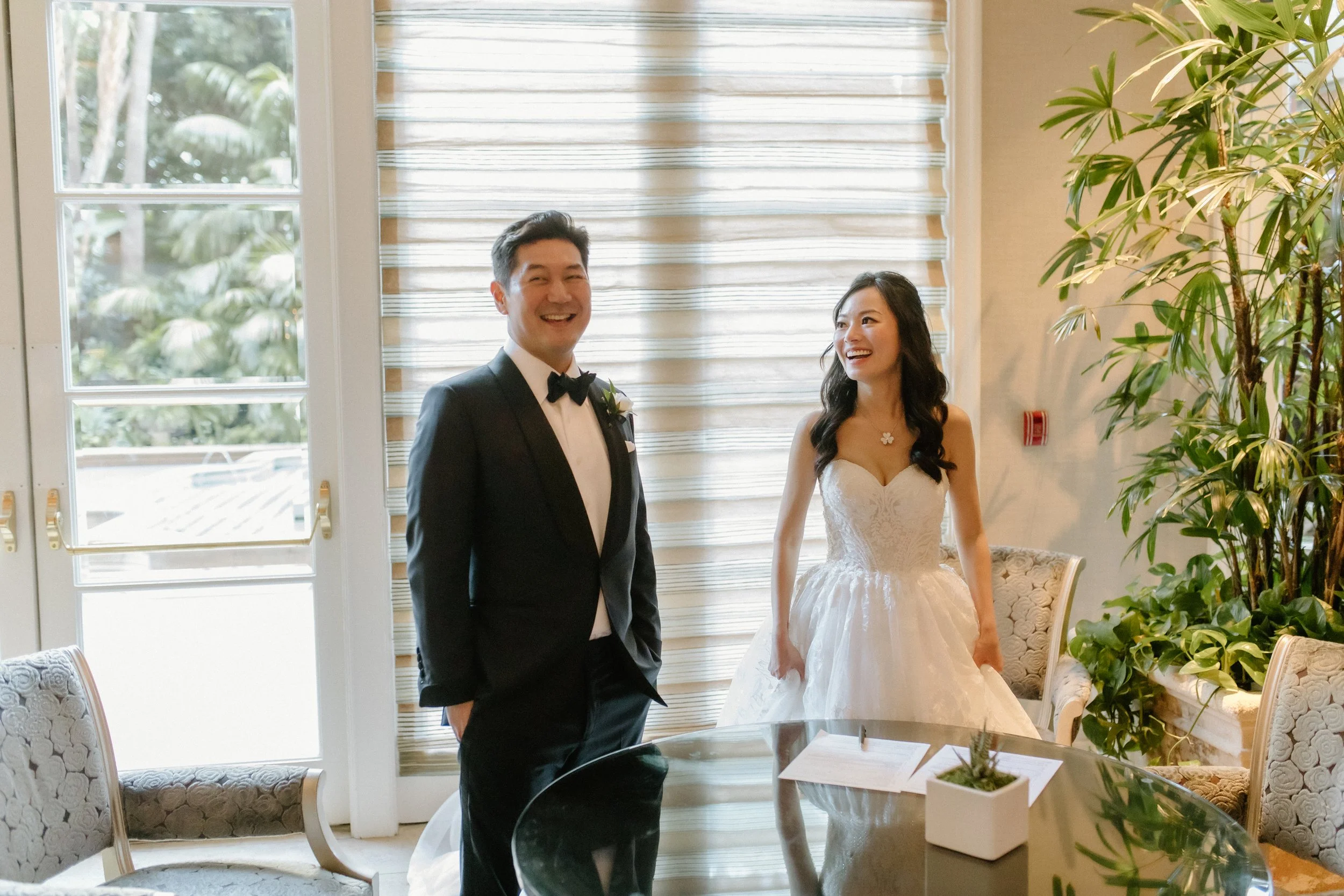 Bride and groom sharing laughter as they anticipate their witnesses signing their marriage license