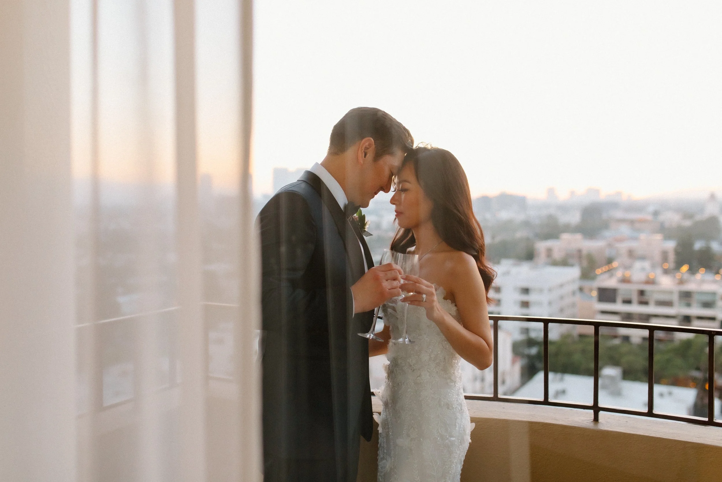 Intimate moment between bride and groom in their wedding suite at sunset at Four Seasons Hotel with Los Angeles skyline in background