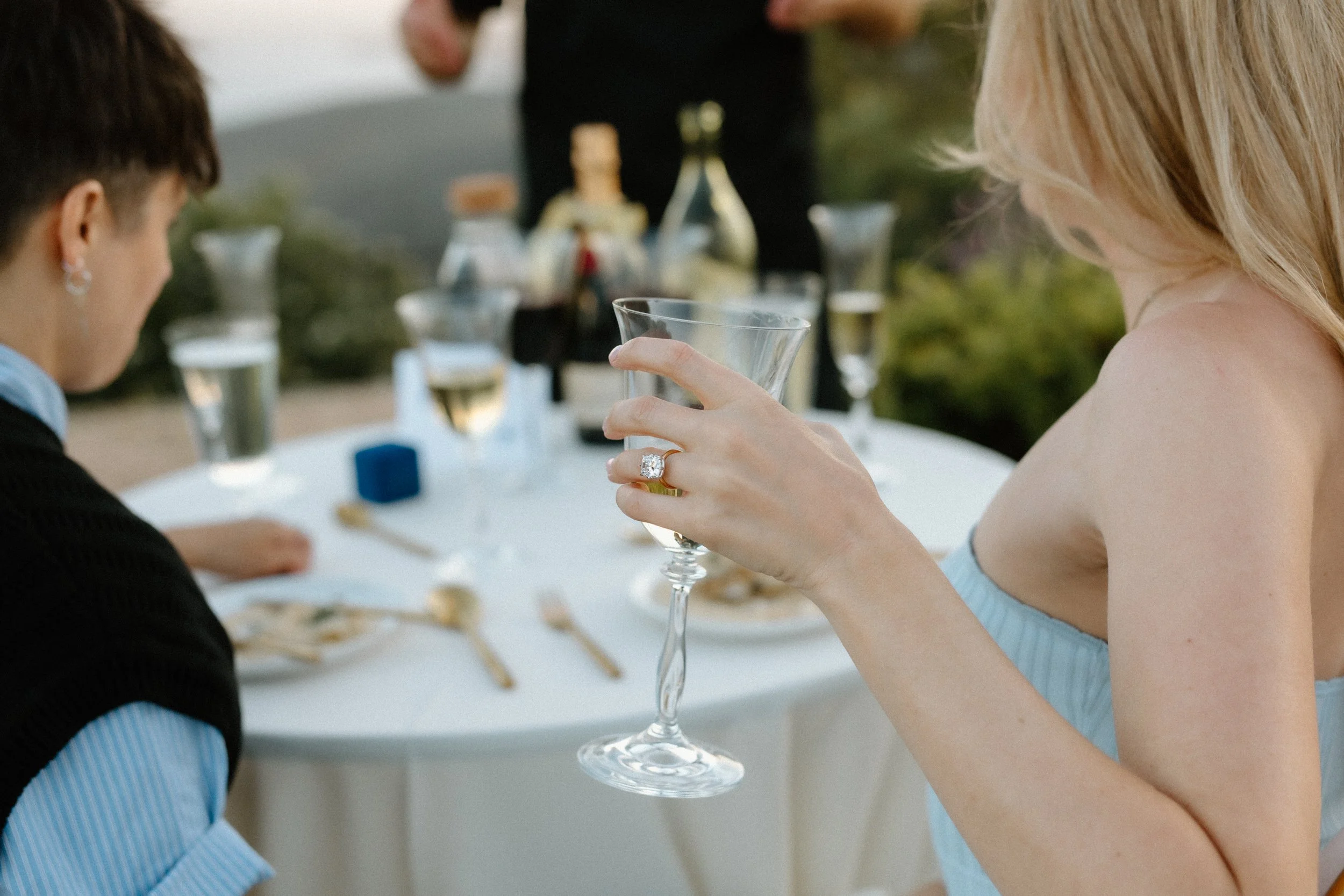 Engagement ring on hand holding glass of champagne