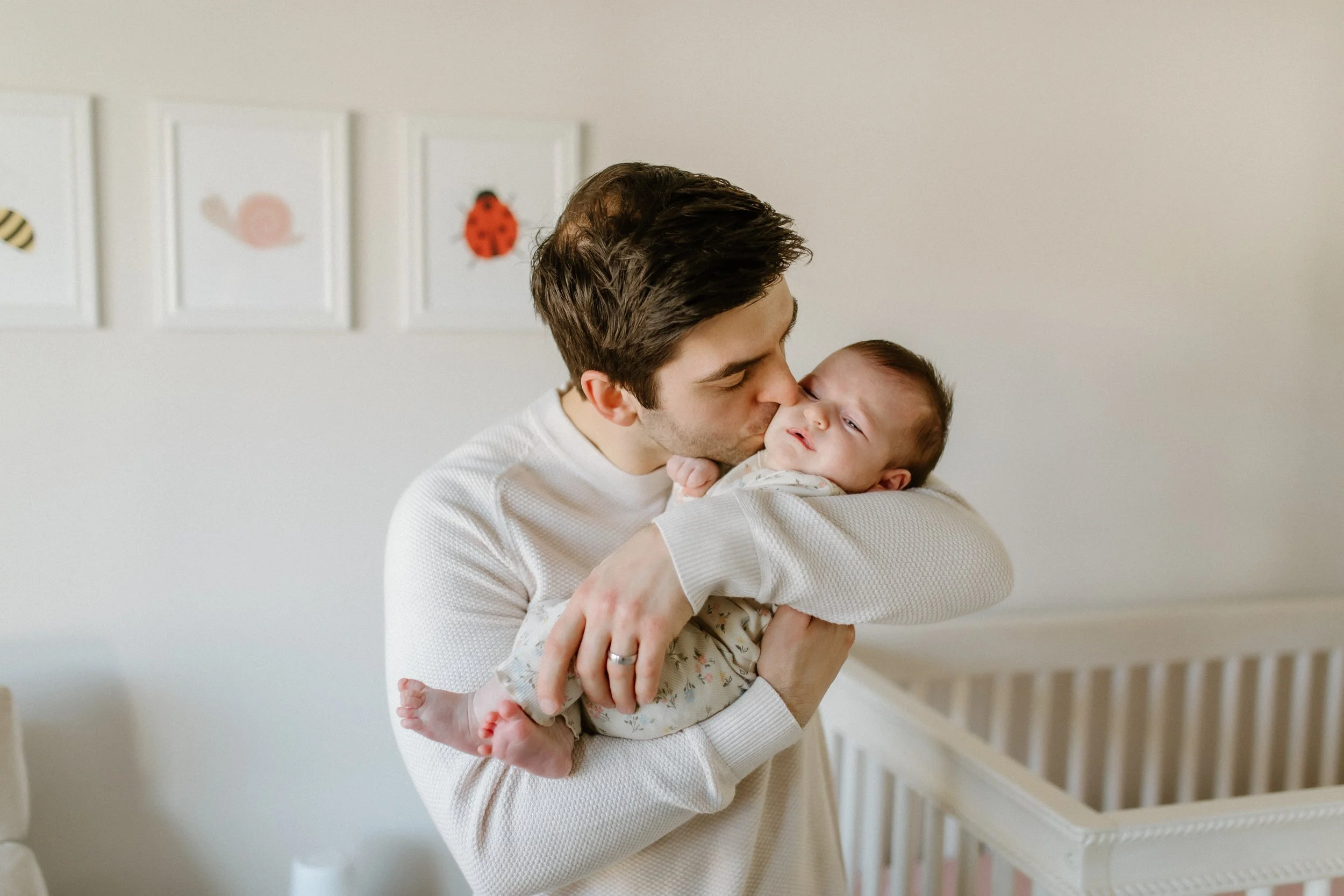 dad kissing new baby