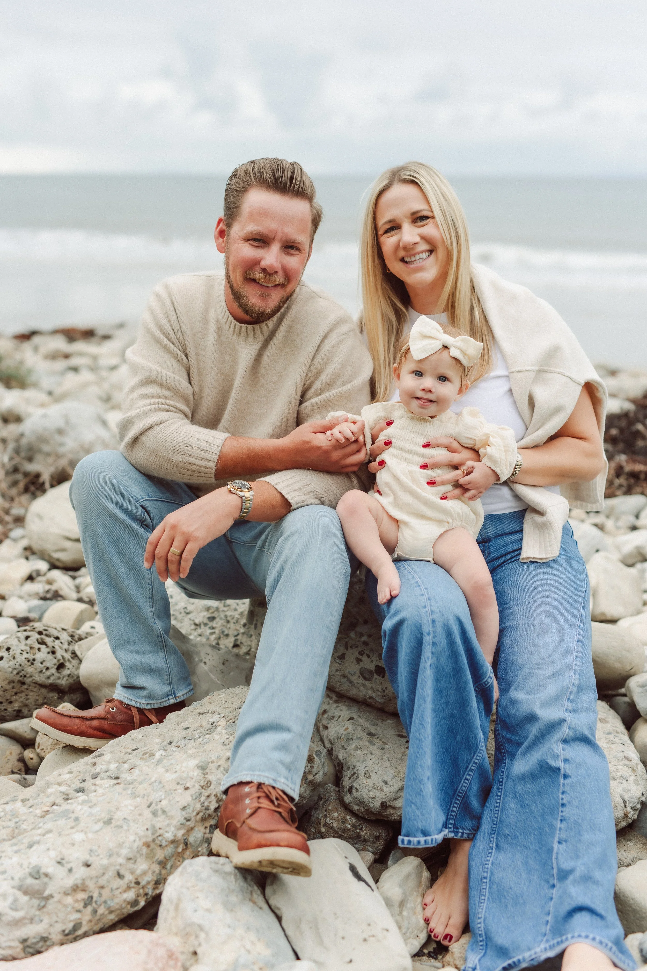 family sits on rocks at the beach
