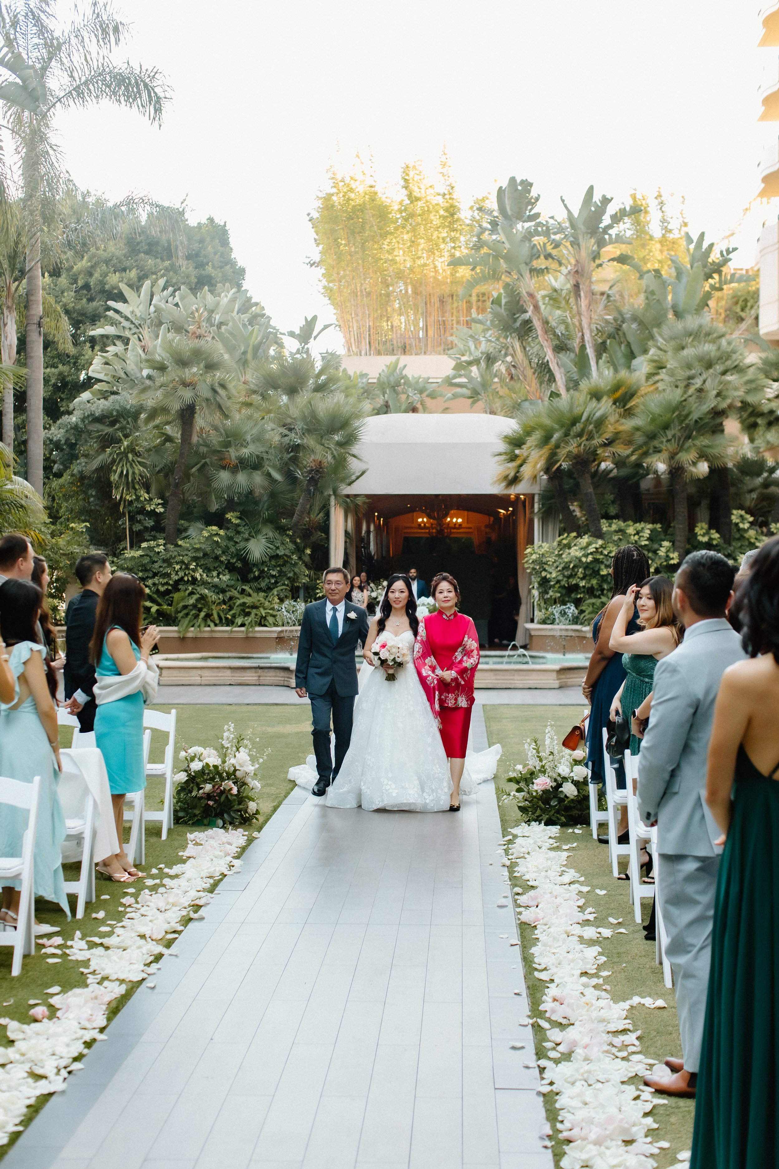 Bride and her mother and father during wedding processional in the garden at Four Seasons Hotel