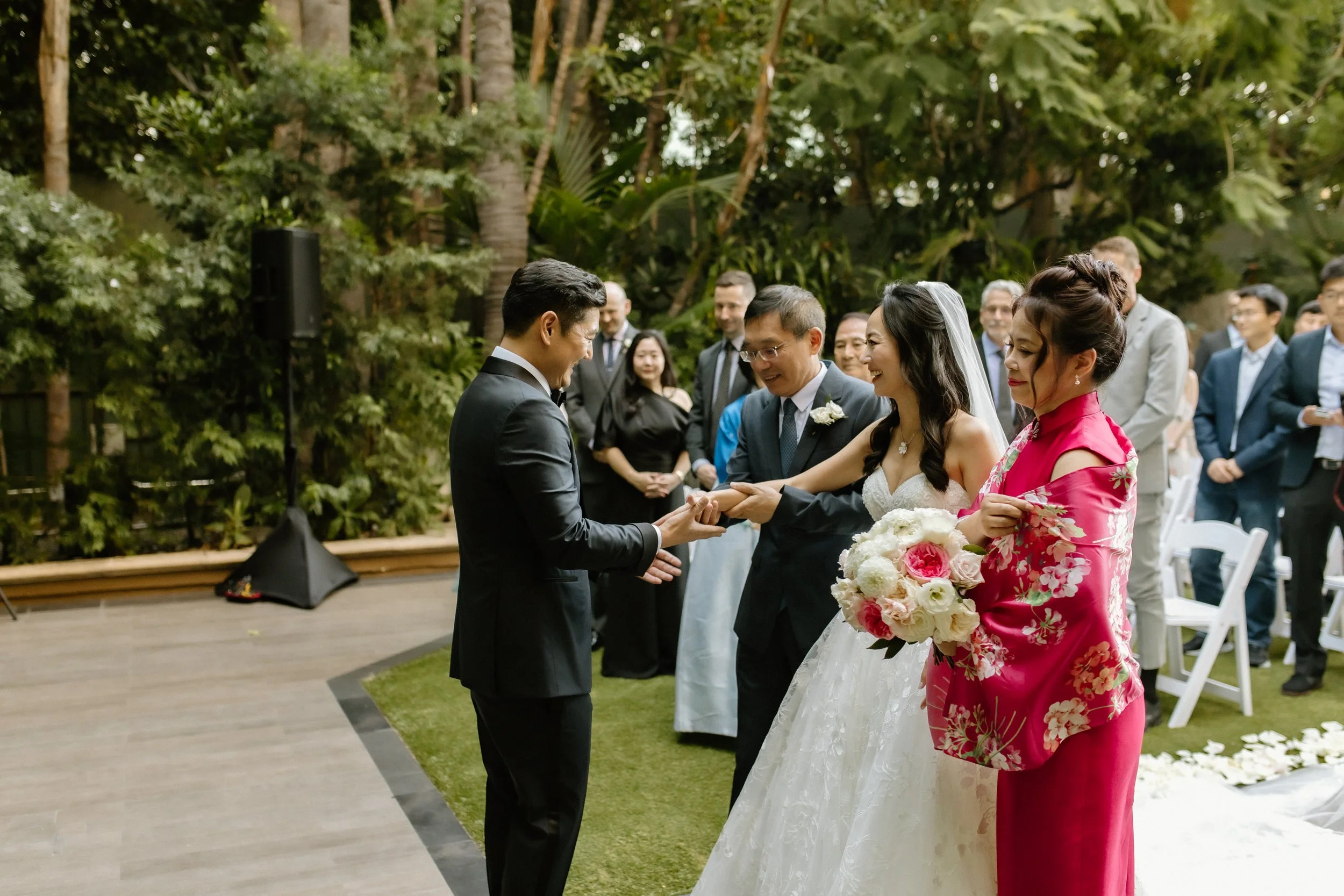Father and mother of the bride join the bride and groom's hands as the begin their wedding ceremony
