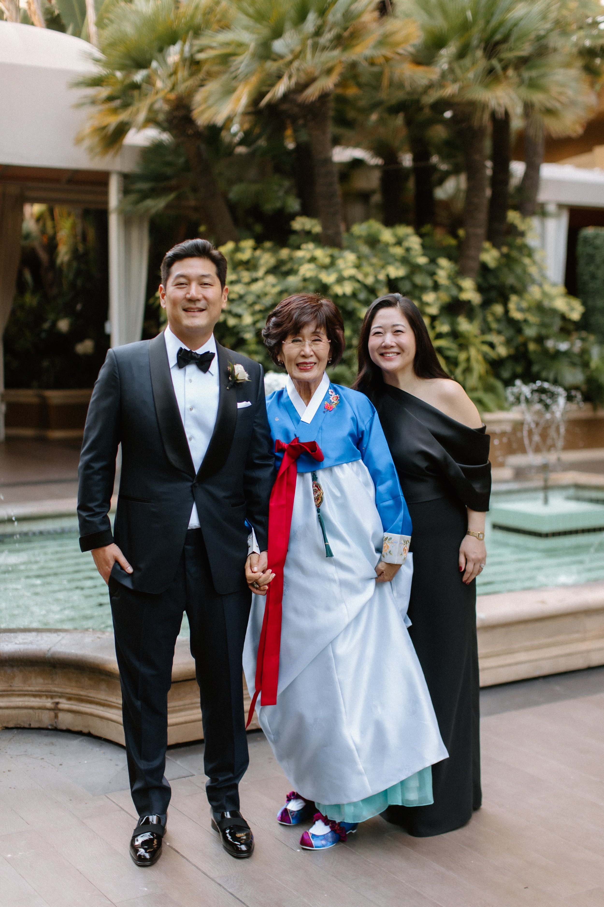 Groom and his mother in Korean Hanbok and sister in a sleek black jumpsuit in the garden at Four Season Hotel Los Angeles