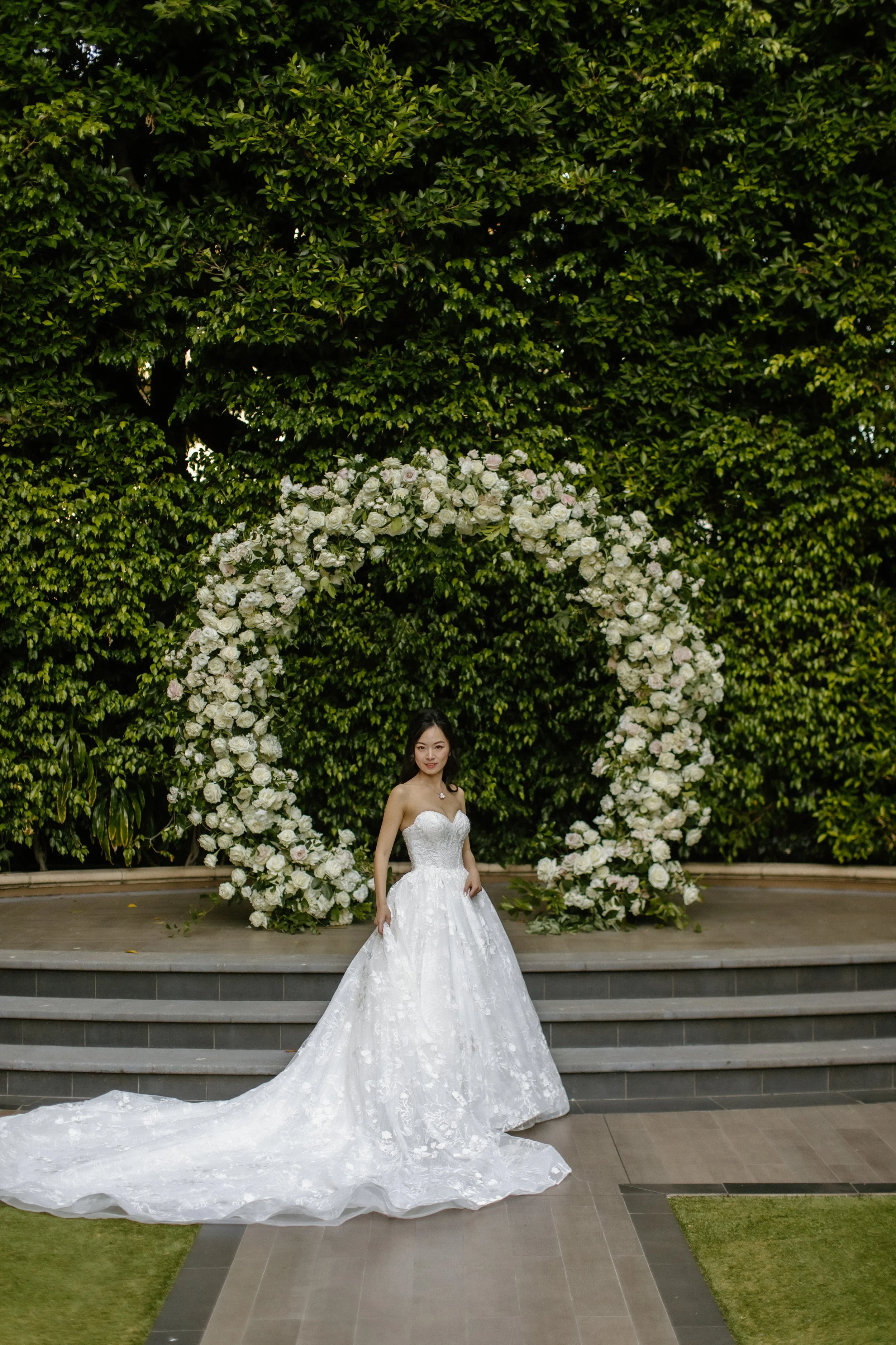 Bride in Pronovias ballgown standing in front of the circular arch in the garden at Four Seasons Hotel Los Angeles at Beverly Hills