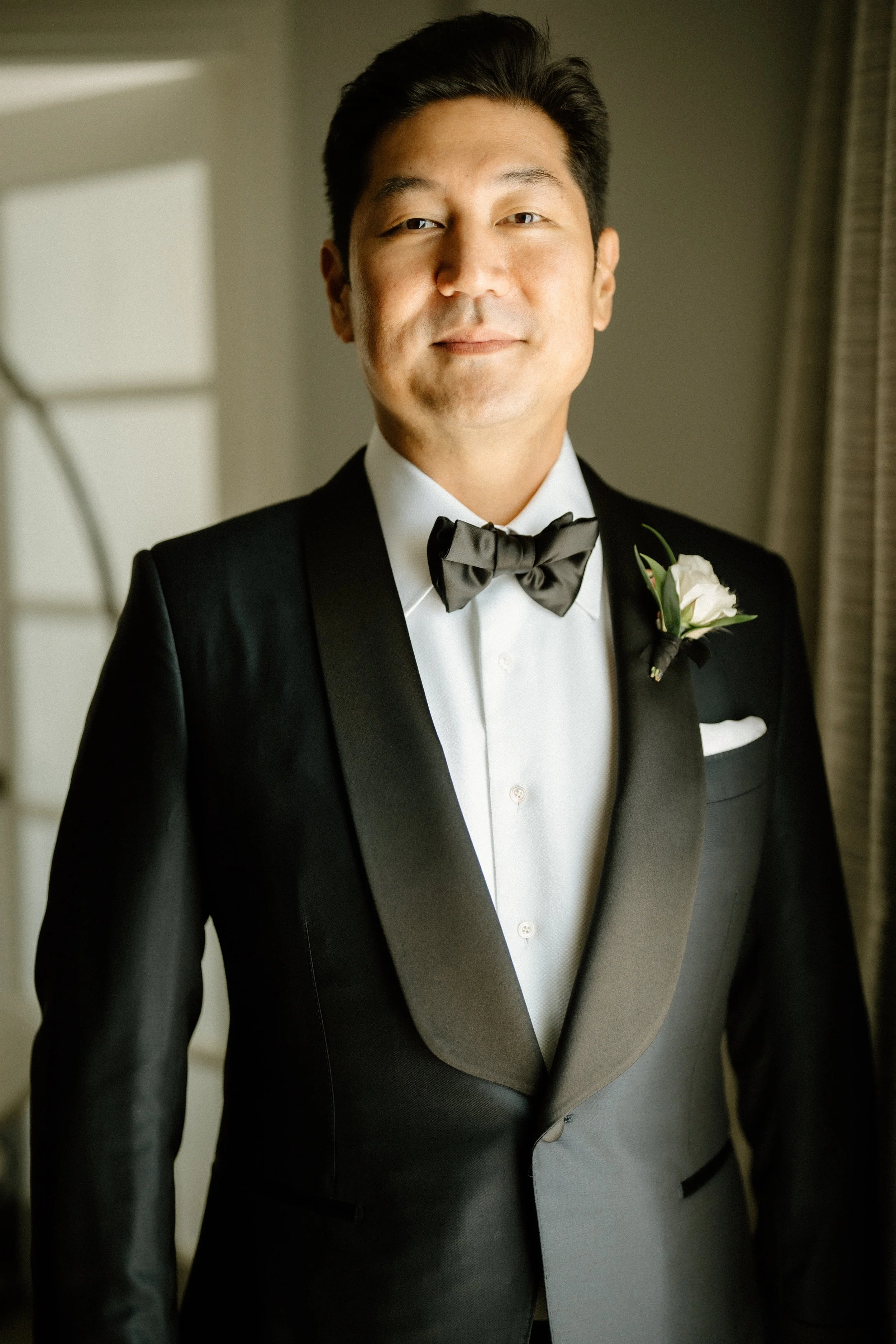 Dapper Groom in Navy and black tuxedo with White Ranunculus boutonniere