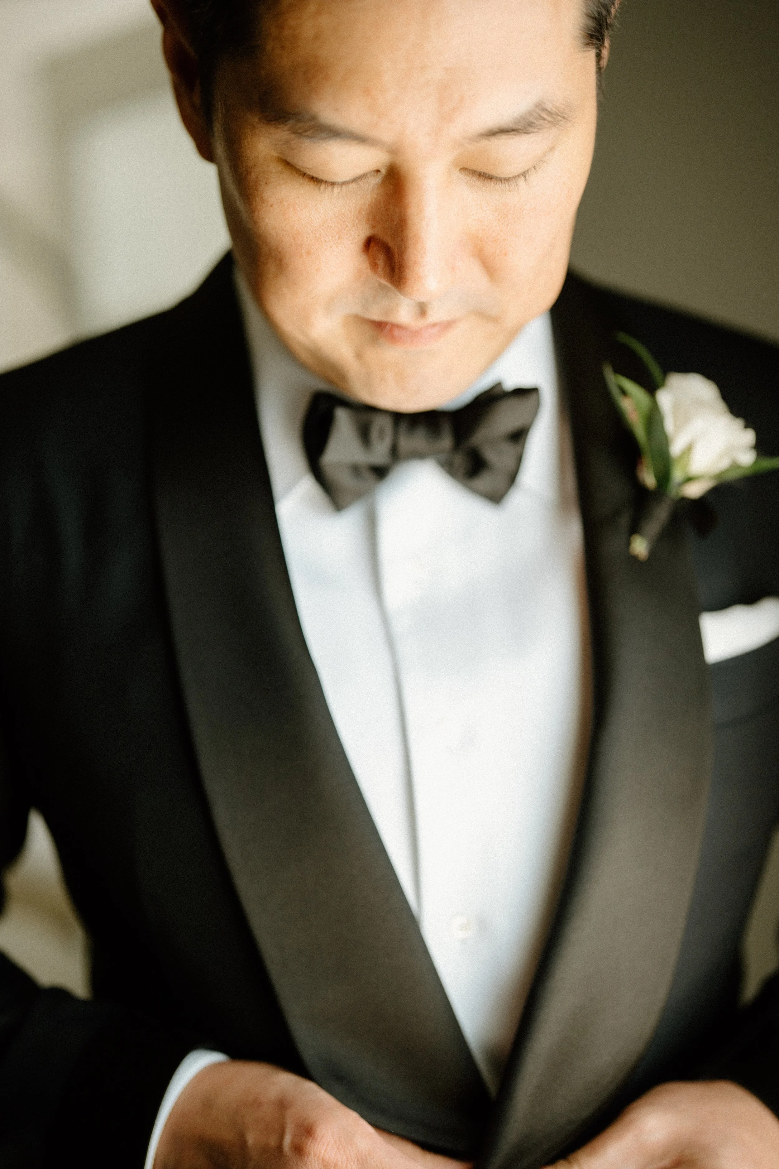 Groom buttons up his tuxedo jacket before heading to garden ceremony at Four Seasons Hotel Los Angeles