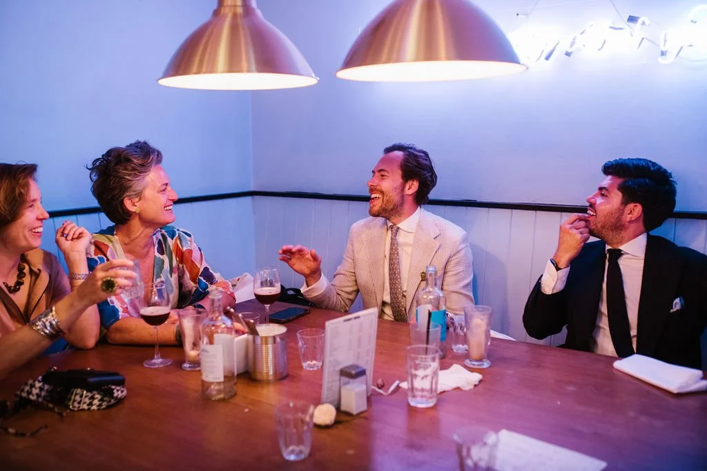 Group of five people enjoying a dinner conversation at a restaurant table.