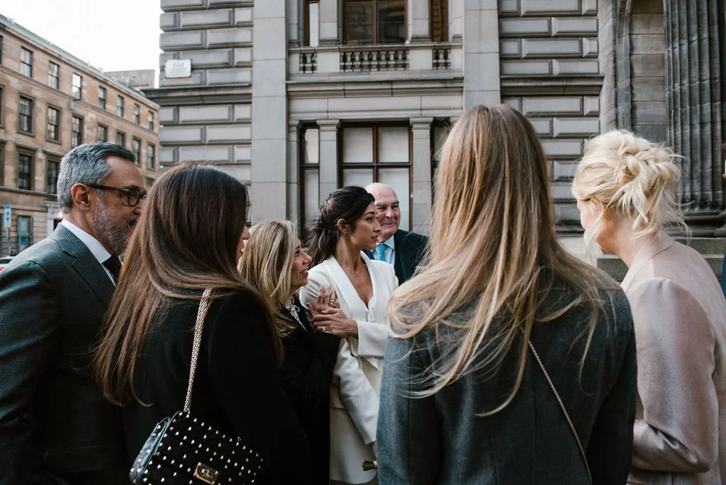 Group of professionally dressed people having a discussion outside an urban building.