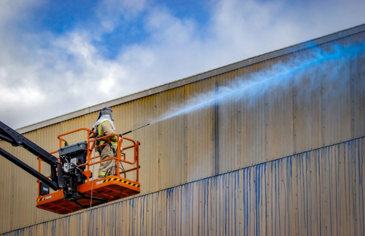  Demolition Specialist Jeff Howard sprays a blue fixative to the Portsmouth Site’s X-333 Process Building to maintain dust suppression on the transite panels. 