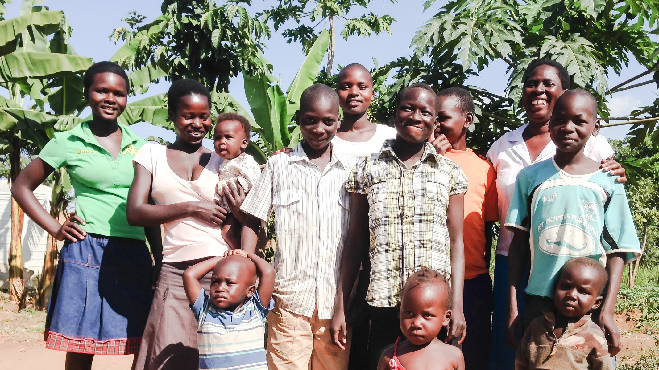 Pader community leader, Anyango Evaline (far right), pictured outside her home in Pader, Uganda. With her focus, entrepreneurship, compassion, and hard work, Evaline has made a living not just for herself, but for many children in the community for whom she has taken in, raised, and put through school.