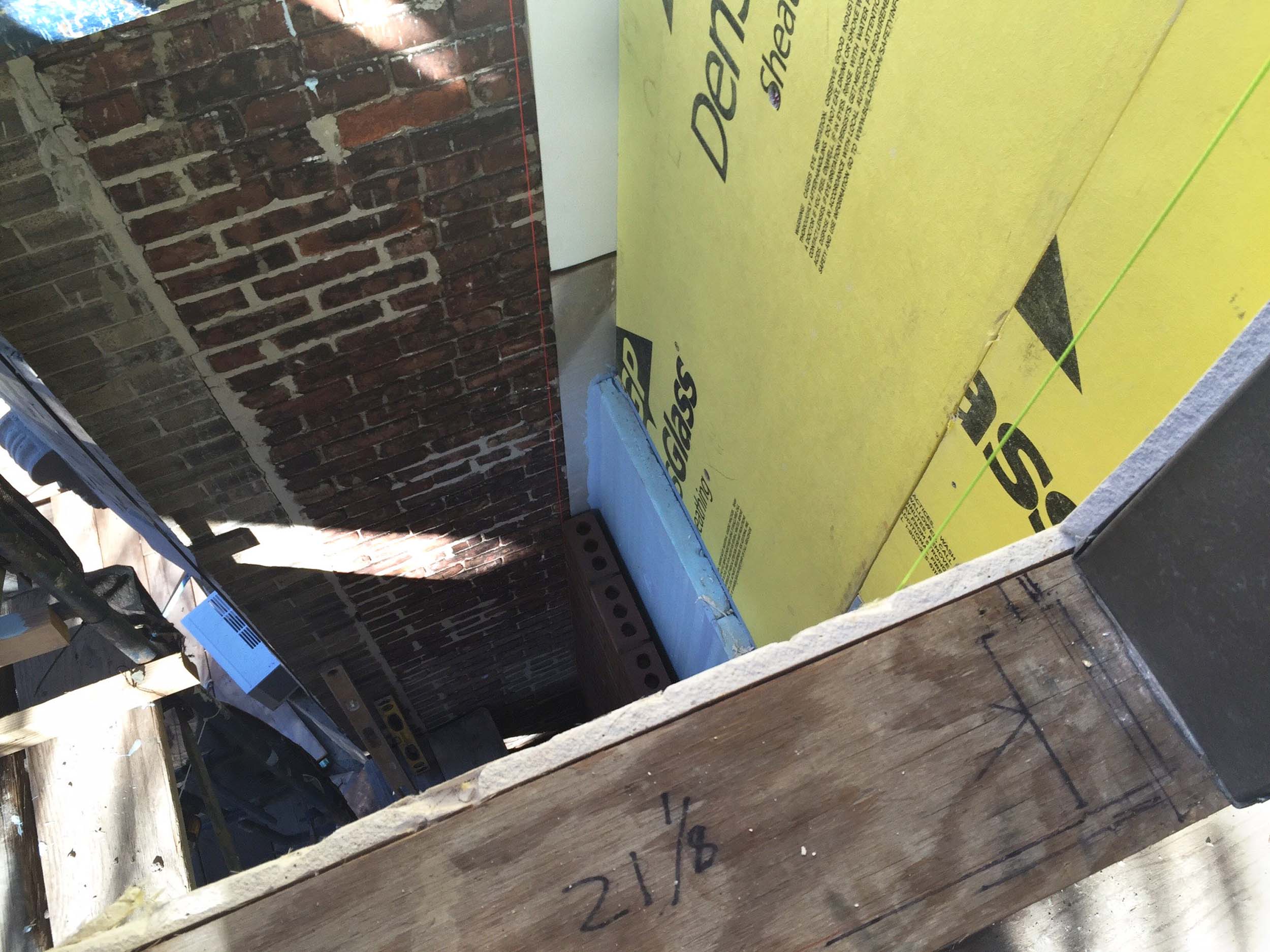   View of an exterior masonry wall being constructed in front of layers of insulation  