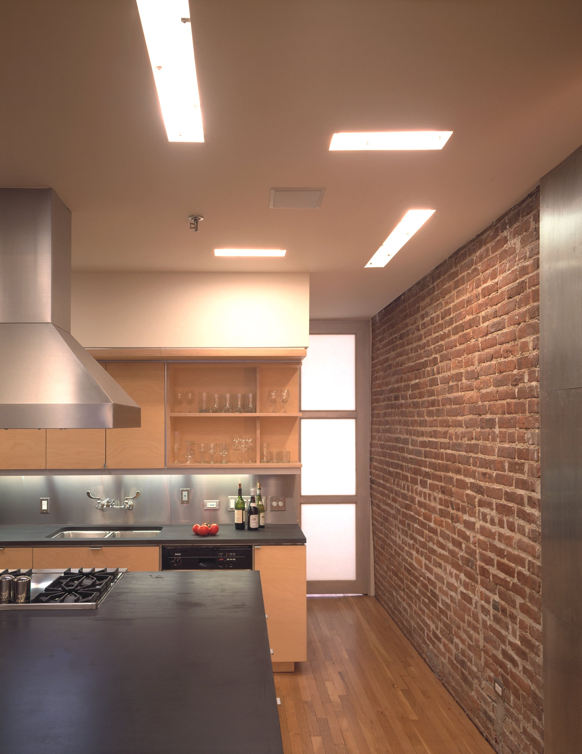 Modern Apartment Loft Renovation | Chelsea Manhattan New York City | Kitchen Exposed Brick Island Black Countertop Custom Cabinets Stainless Steel Backsplash | RES4