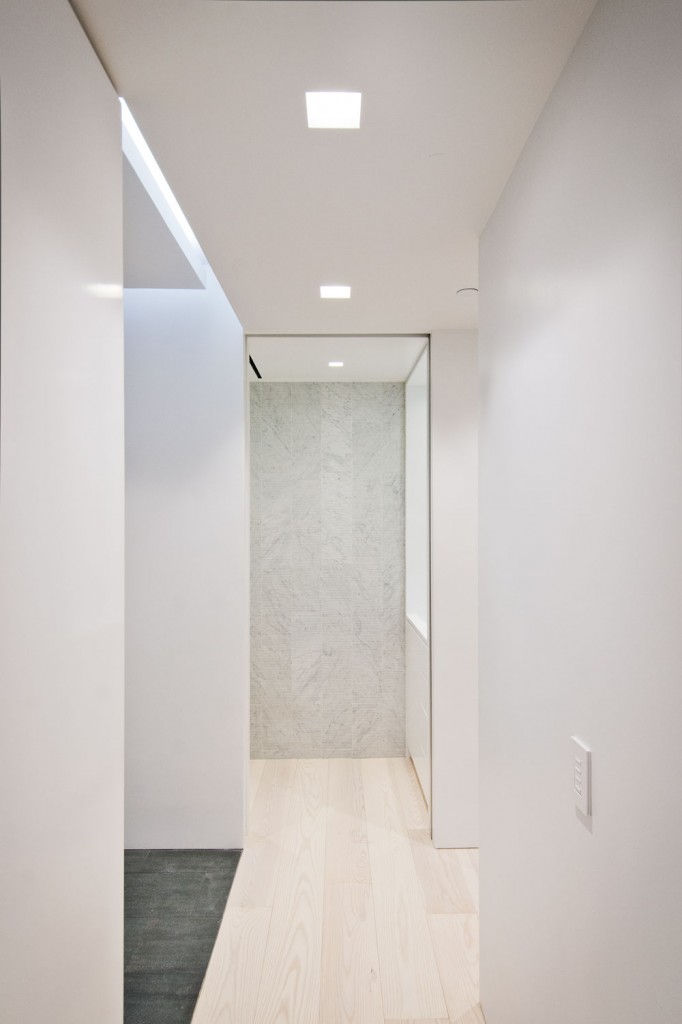   Hallway  -  minimal hallway design with recessed linear lighting strips in soffit and hardwood floors throughout.  