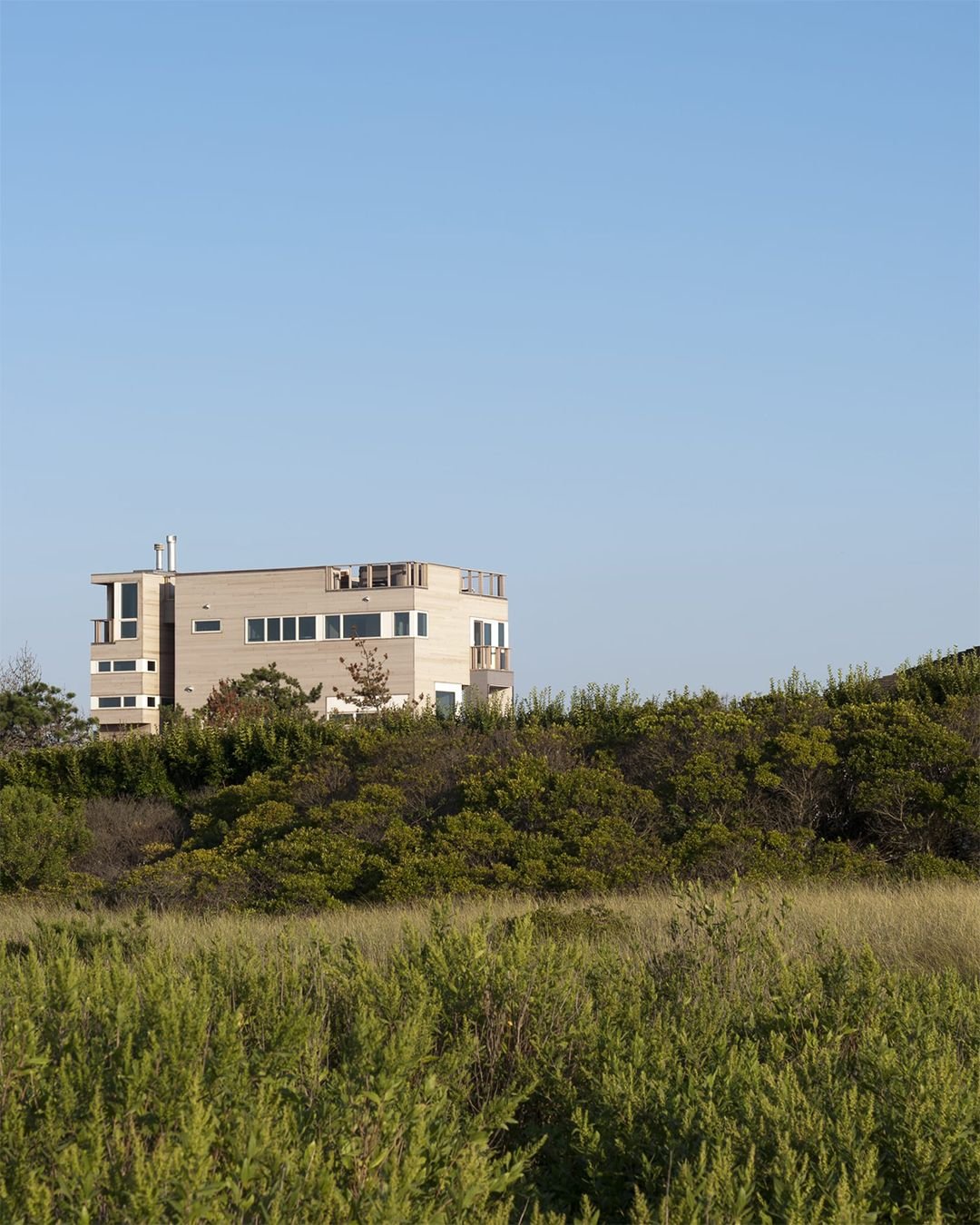 Located off renowned Dune Road on one of the last remaining oceanfront flag lots, this compact 2,200-SF beach house makes the most of every inch. The two-story design includes four bedrooms and a small office, all carefully arranged within its modest