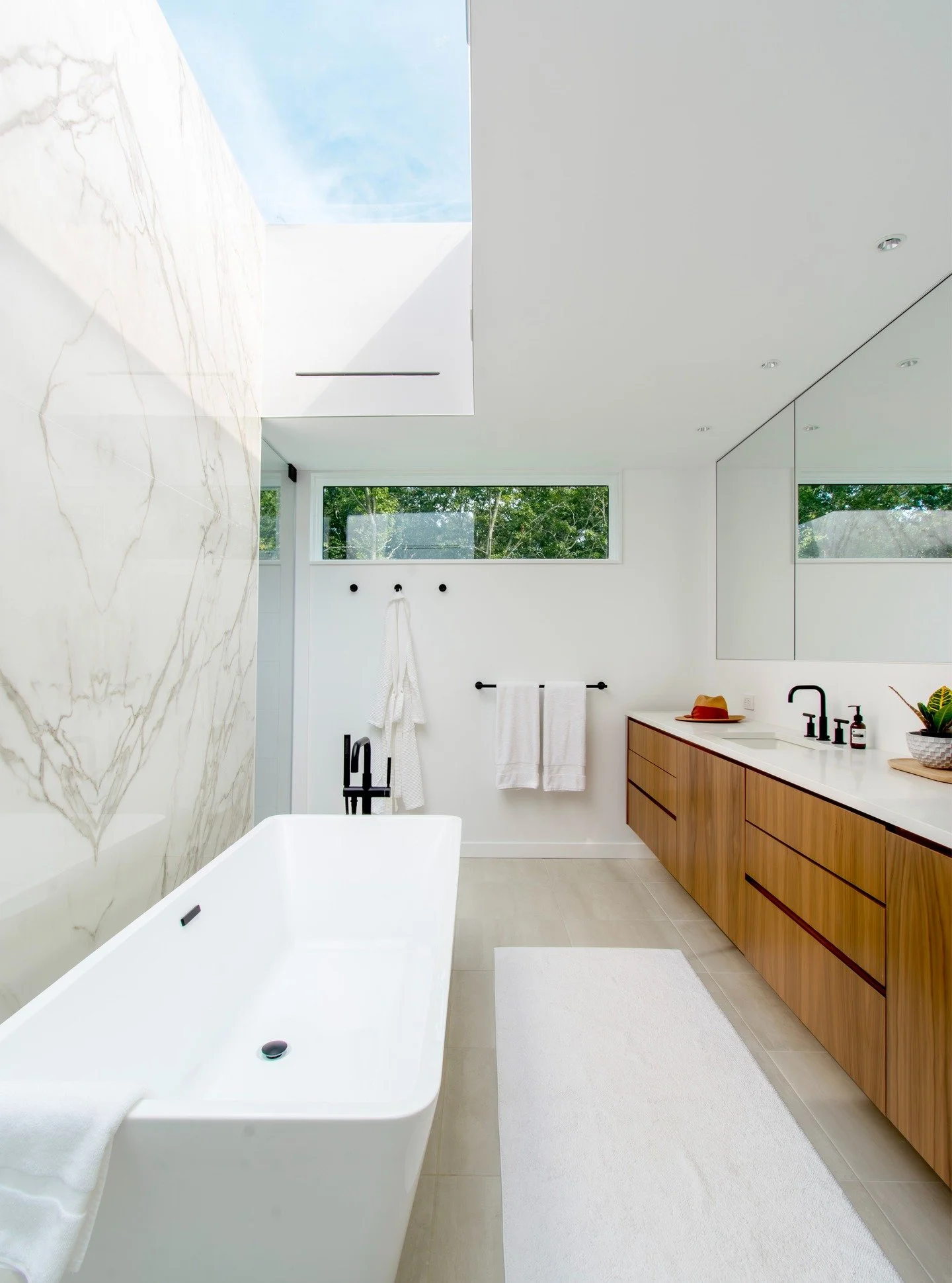 MODERN MODULAR primary bath. Built offsite.

This primary bath was largely completed in the factory before delivery - floating walnut vanity, large-format tile, custom Corian trim, radiant floor heating. 

The custom vanity uses integral pulls and si