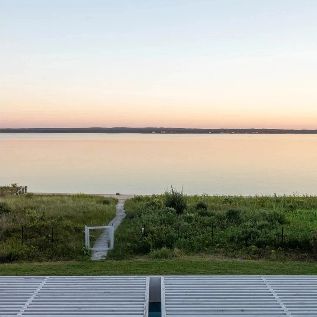 The trellis at our MODERN MODULAR Riverhead House extends the living spaces toward the pool and Peconic Bay, creating an outdoor room while filtering sunlight. Inside, full-height glazing maintains a continuous connection to the landscape.

Riverhead