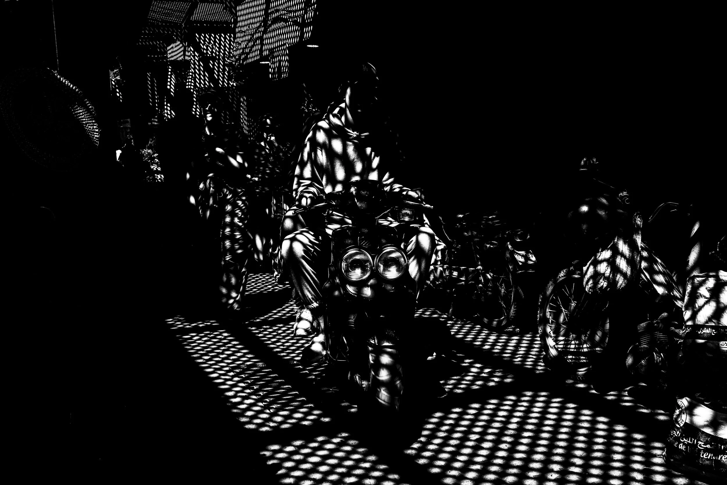 Man rides Motorcycle through Shuk Shadow B&W Marrakech Morocco.JPG