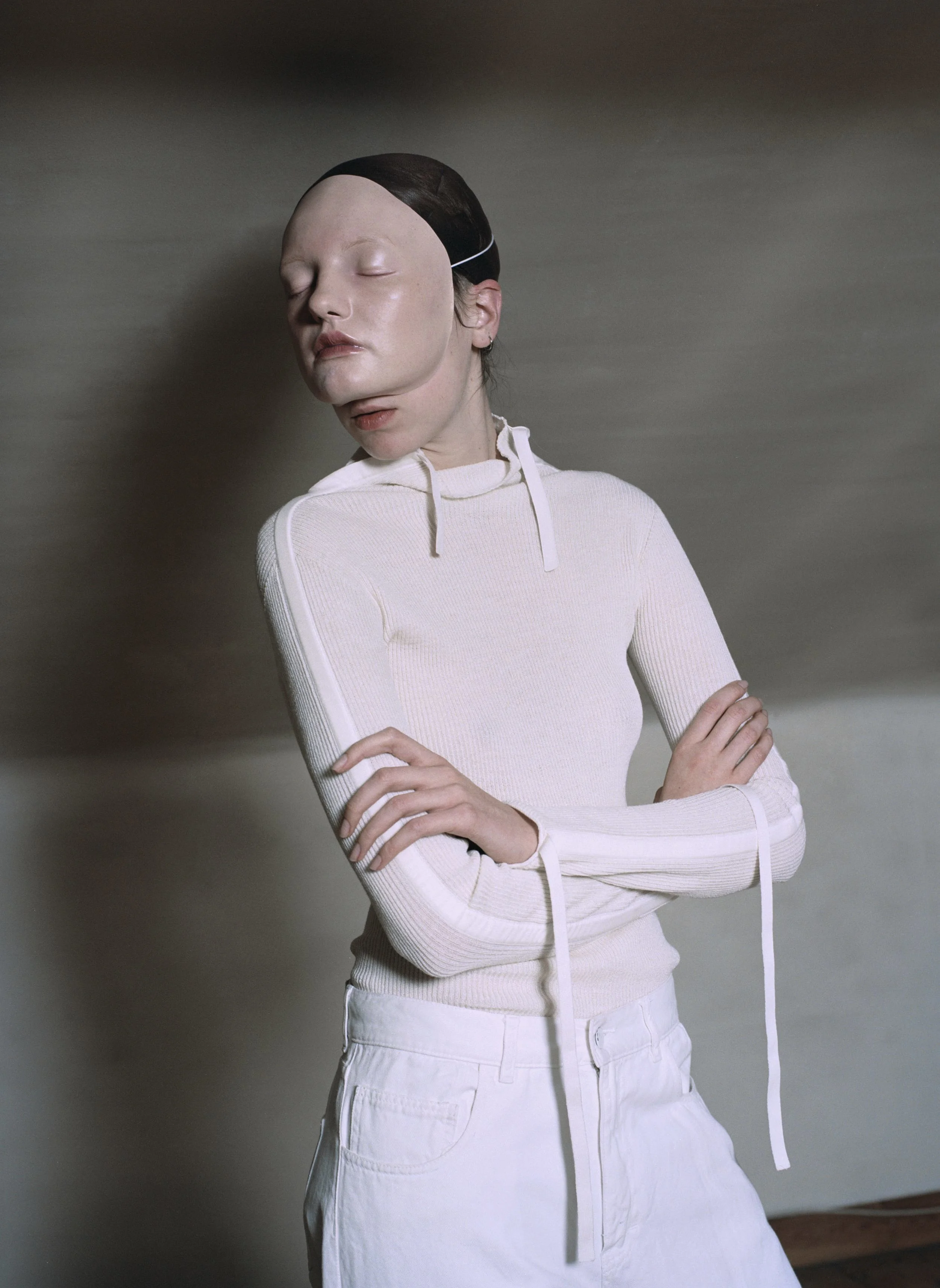 High neck jumper with bone wool silk tapes CÉLINE, white denim trousers JACQUEMUS.