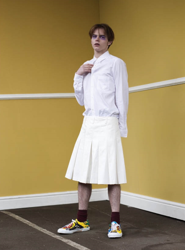  Long white cotton jacket, white shirt with shoulder and back slit details, pleated shorts and hand painted canvas plimsolls. 