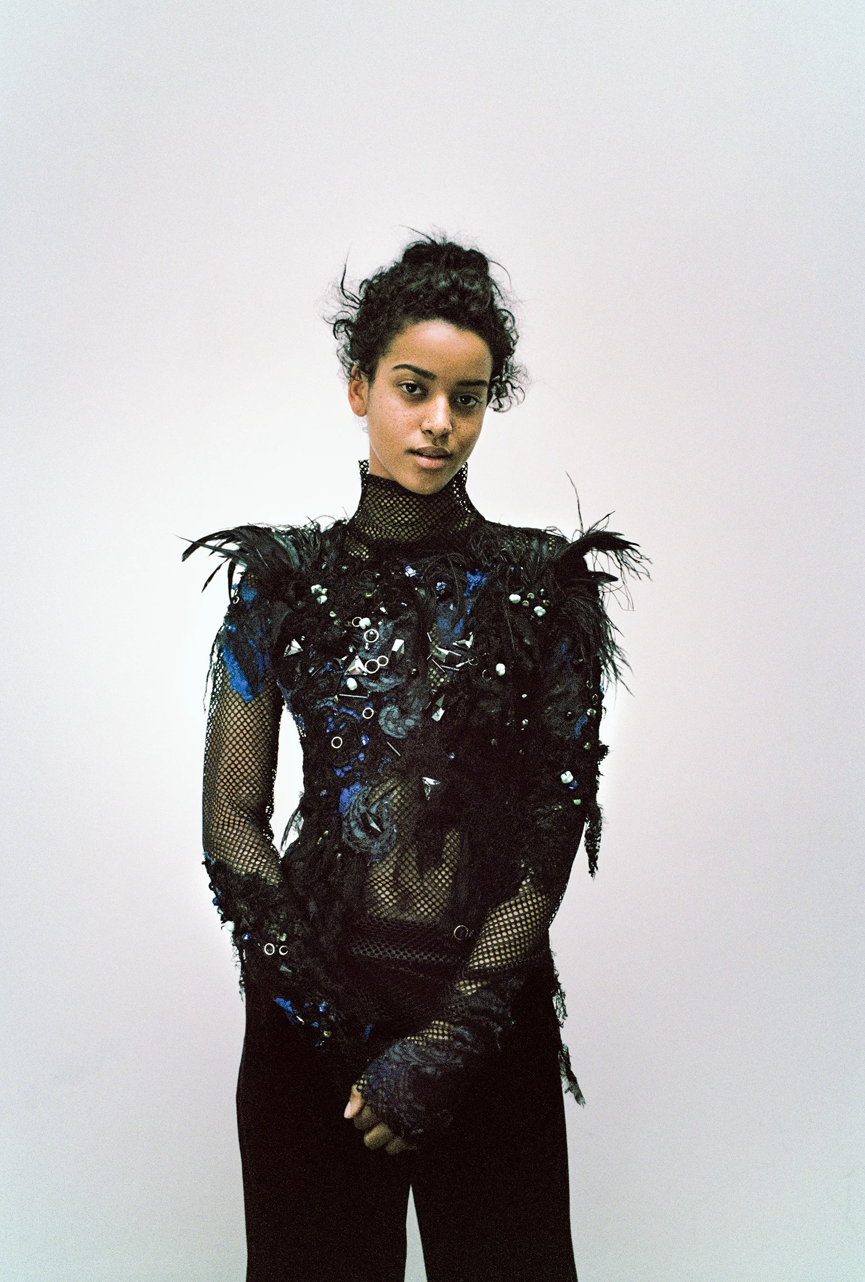Feather embellished fishnet turtleneck and wide leg velvet trousers 
