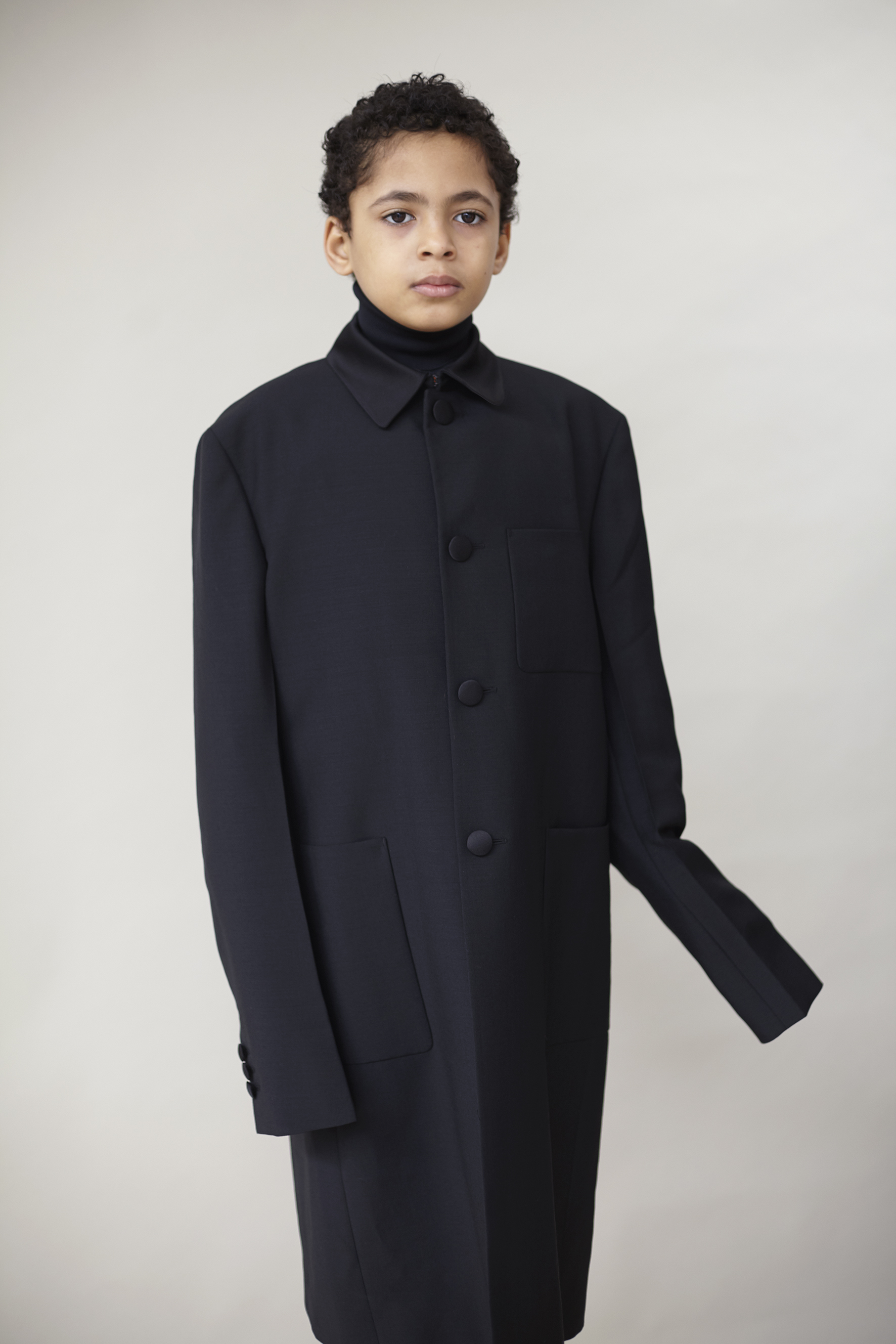  Black wool and satin coat and technical jersey turtleneck PRADA, white velvet tights WOLFORD. 