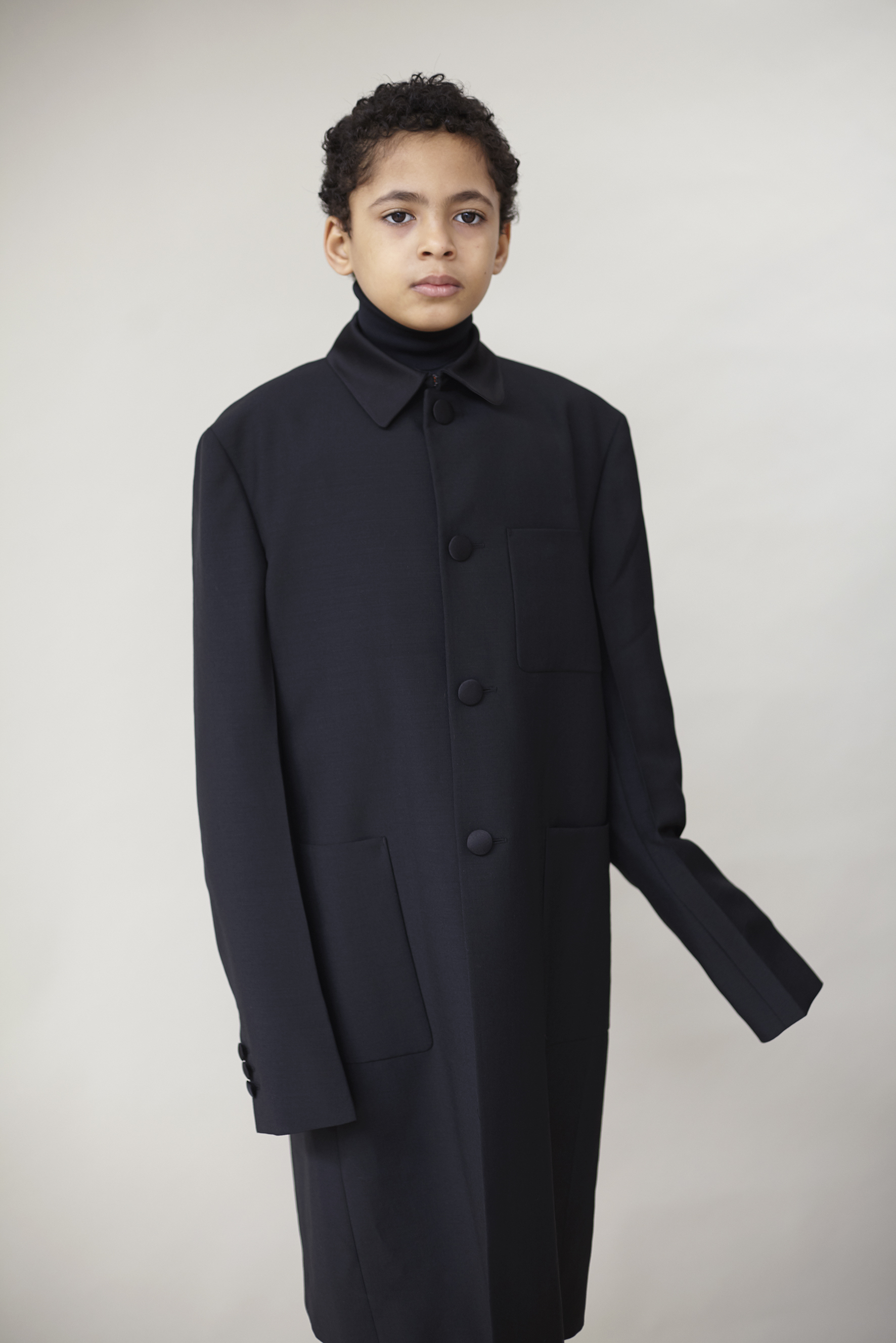 Black wool and satin coat and technical jersey turtleneck PRADA, white velvet tights WOLFORD.