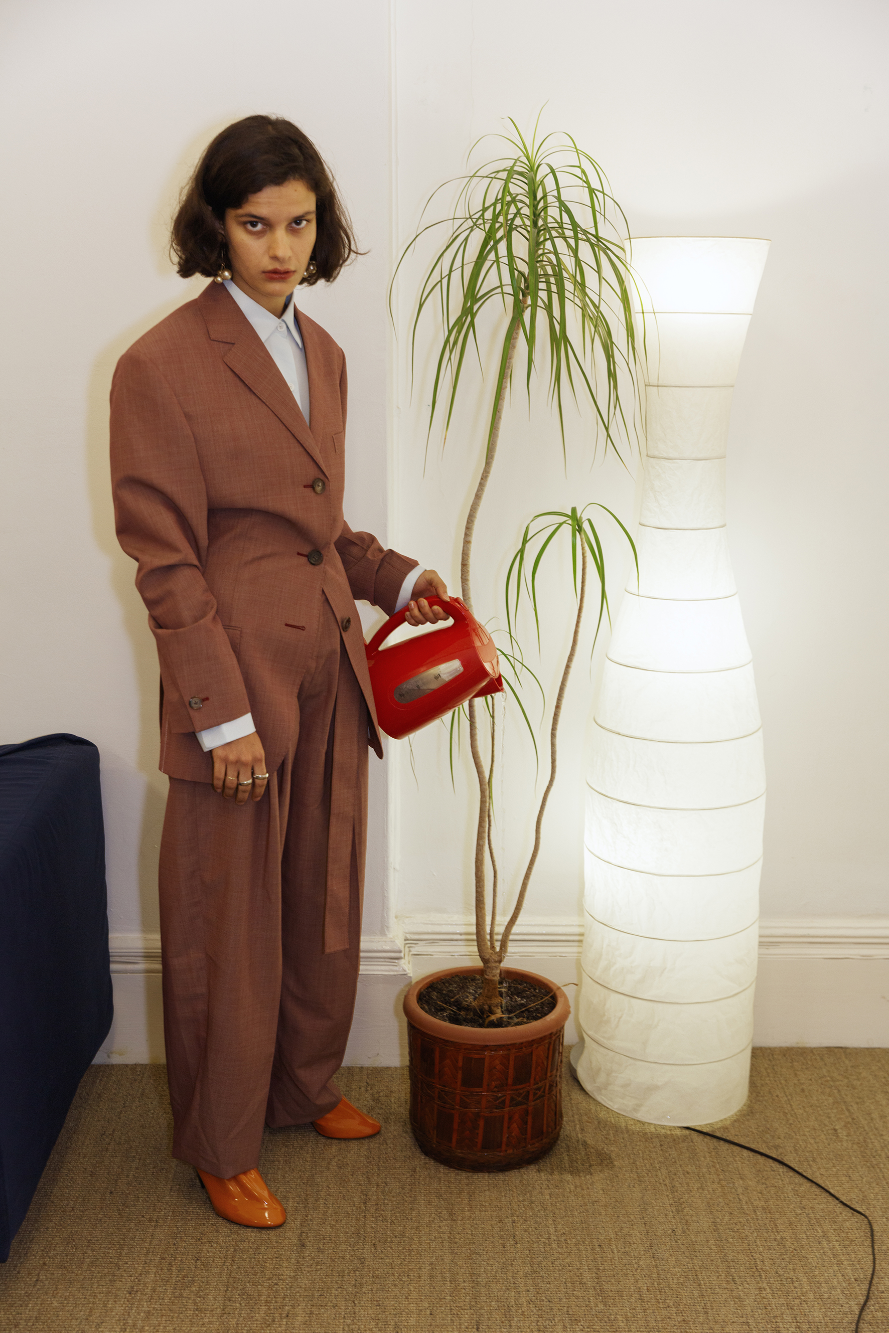  Brick “fil a fil” wool and mohair tailored jacket and high waisted belted trousers, oversize shirt, orange soft patent calfskin pumps and ivory gold dot triple pearl earrings CÉLINE, band gold ring BALENCIAGA,&nbsp;silver ring FESWA. 