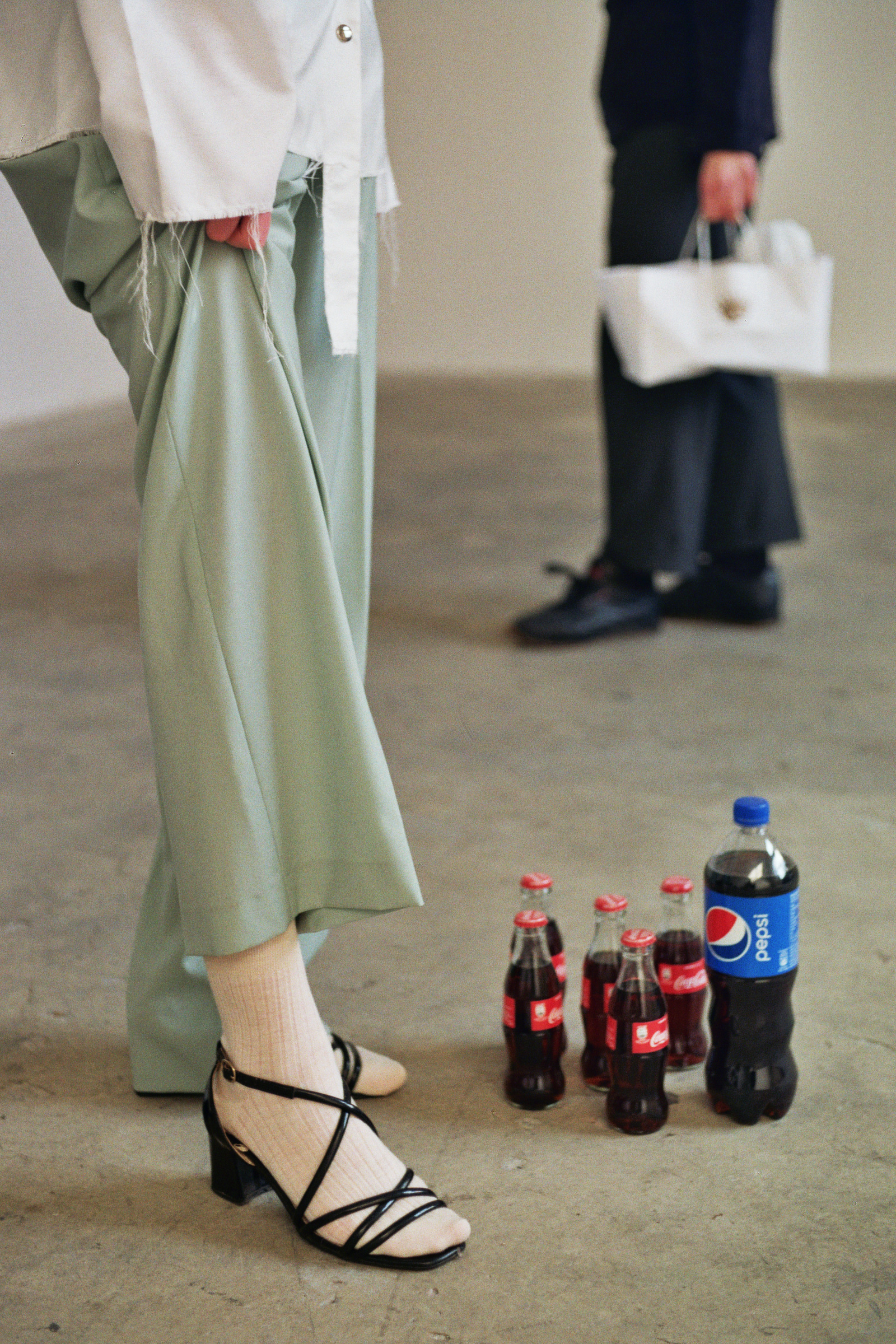  White organza shirt: Traffico, light wool trousers: Pence1979, socks: Maria La Rosa, sandals: stylist own.  Art piece: Rebel Rebel   1lt of Pepsi in 5 bottles of Coca - Cola and 1lt of Coca-Cola in one bottle of Pepsi  Artist: Roberto Fassone 