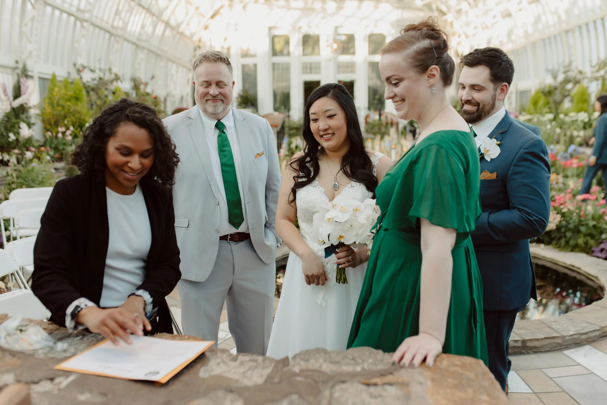 Signing the marriage license at Como Zoo in the sunken garden with the wedding planner showing the witnesses and bride and groom where to sign