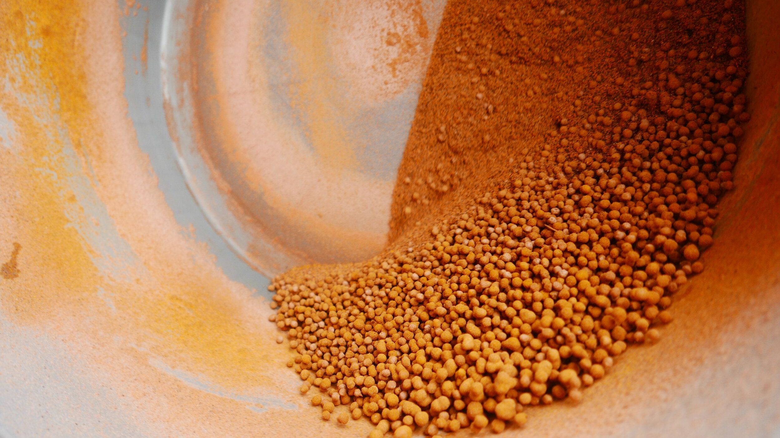 Detail of seed coating with a plastic pan in a cement mixer.