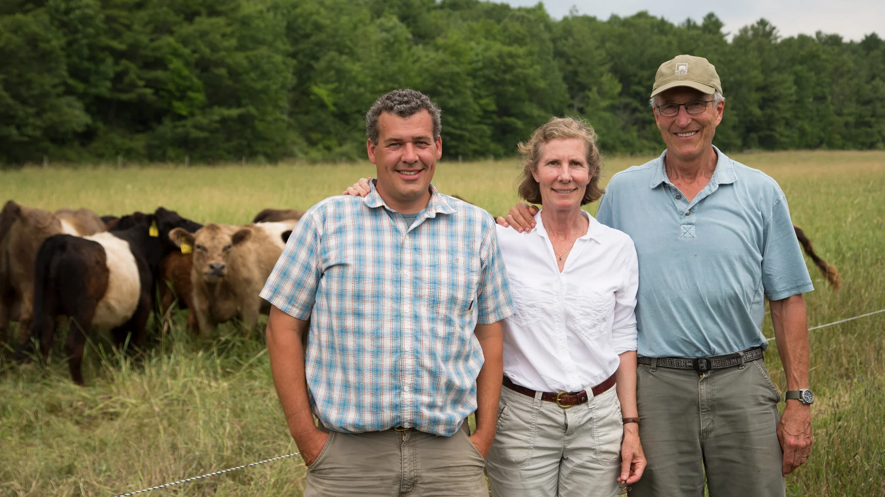 Ed, Diana and Peter standing in front of our herd of Belted Galloways.