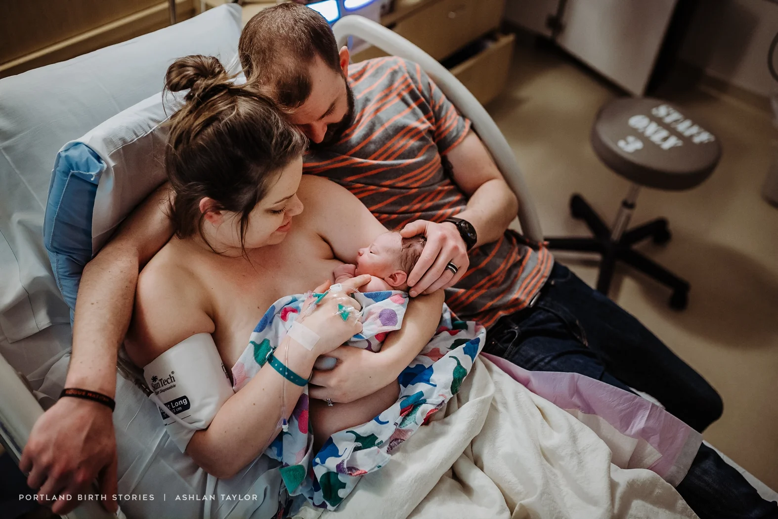 Mother and father hold newborn baby after hospital birth