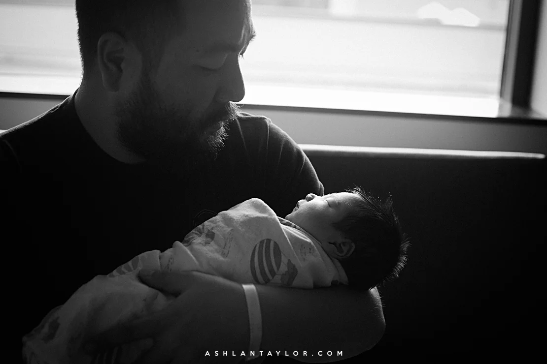 Father holds baby newborn after birth