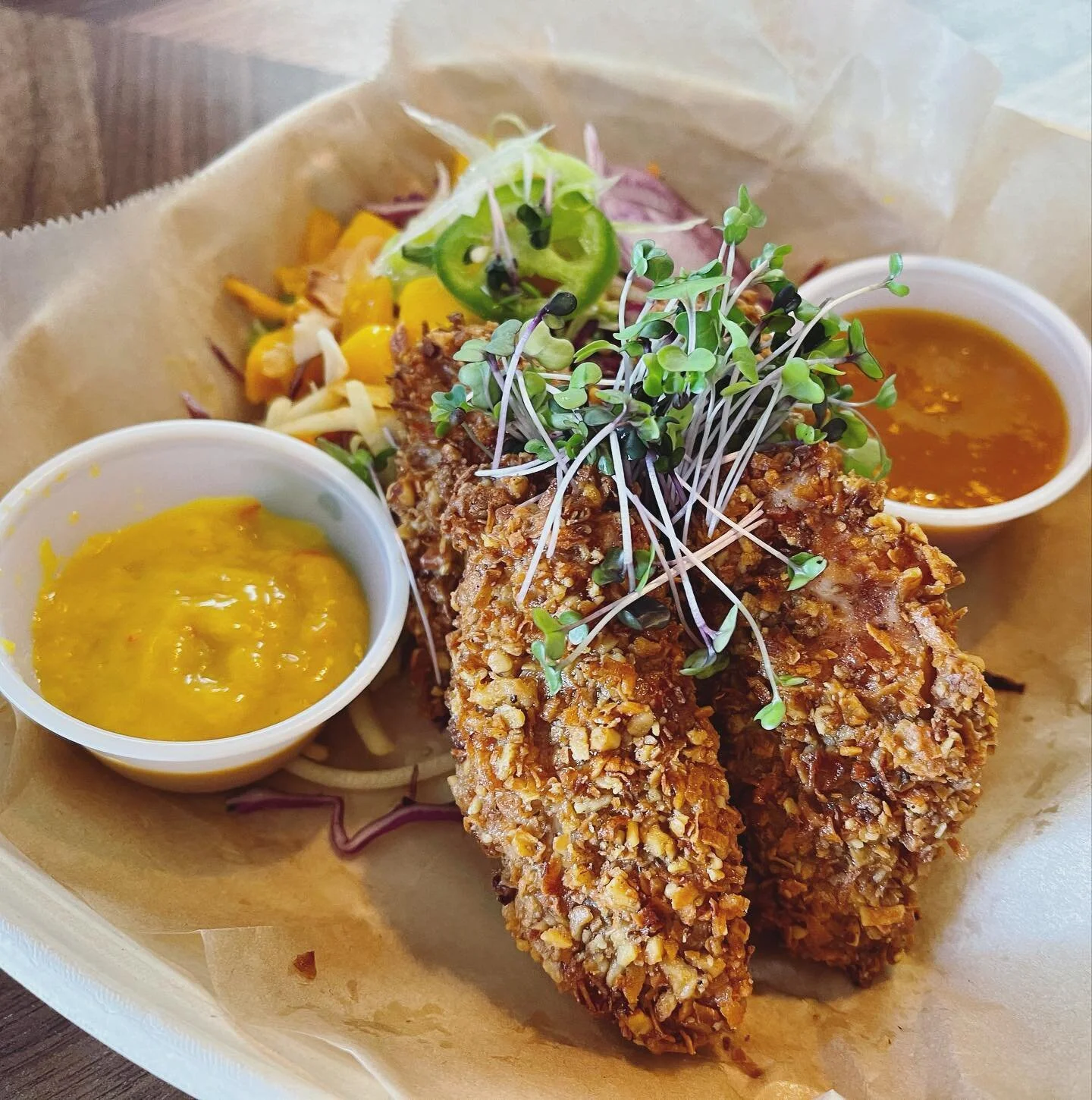 Gluten-free coconut walnut encrusted @pasturebird chicken breast strips with Tropical Slaw Pineapple Ginger, Toasted Coconut, Fresh Mango, Mango Sauce, and Smoky Mango BBQ with no added sugar. // Enclave Caf&eacute; now open Wed-Sun 12-8pm and can al