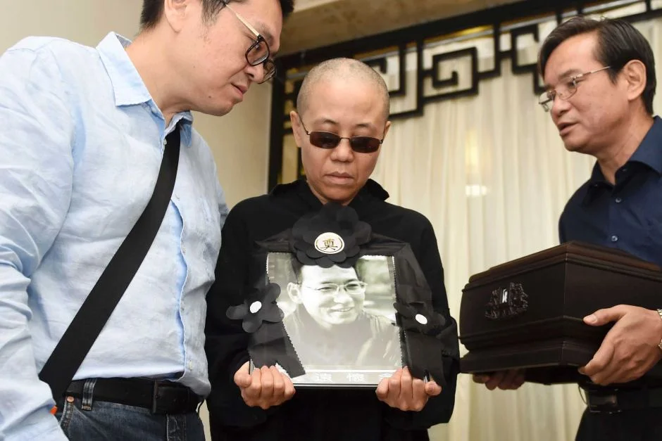 Liu Xia holds a portrait of Liu Xiaobo during his funeral . AP: Shenyang Municipal Information Office