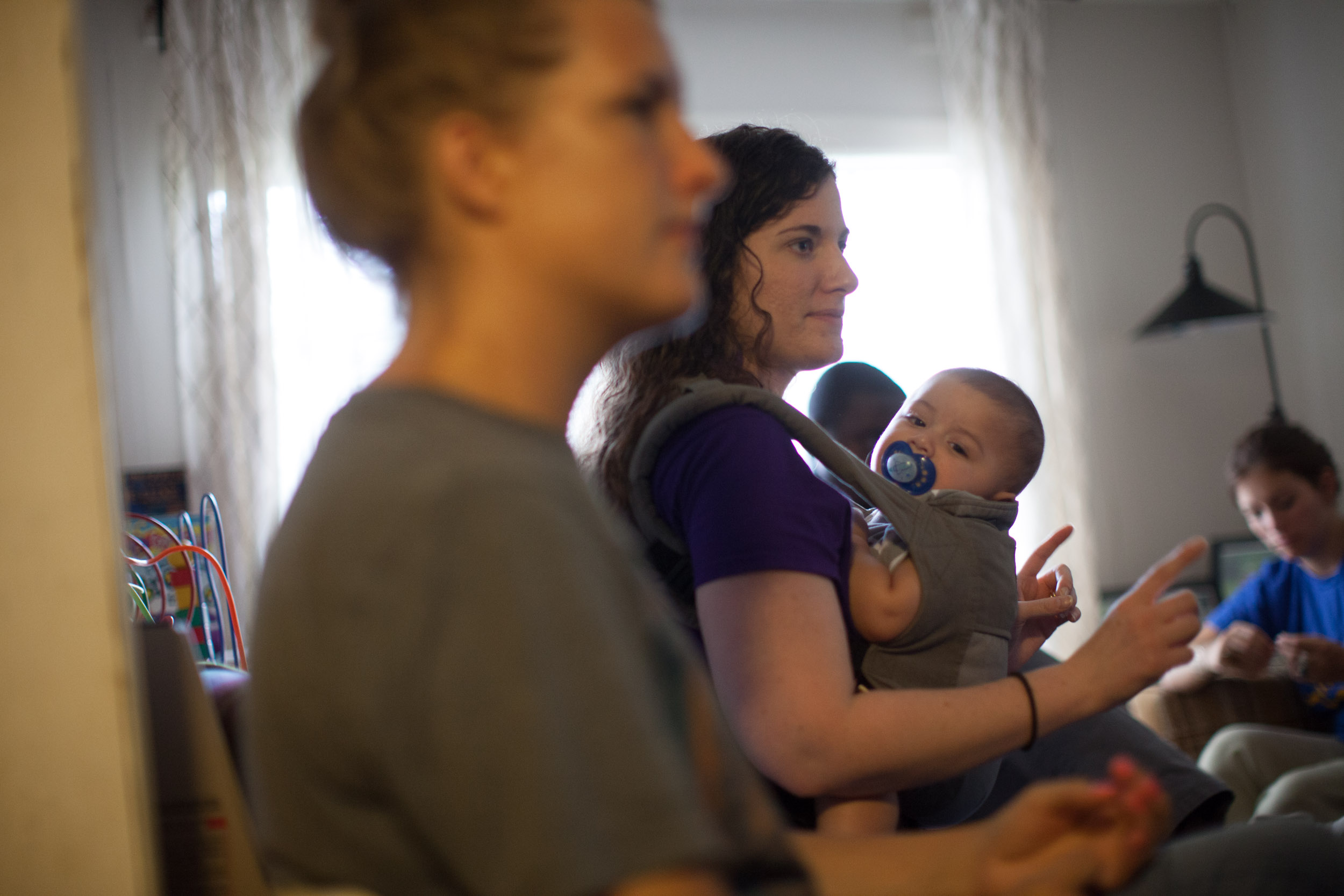 Emory University student Debra Kozowski, left, listens as Katie Valencia, center, holding her son Oscar, briefs other volunteers on visits they will be making to Stewart Detention Center , Saturday, Sept. 12, 2015, in Lumpkin, Ga. (Photo by Branden Camp)