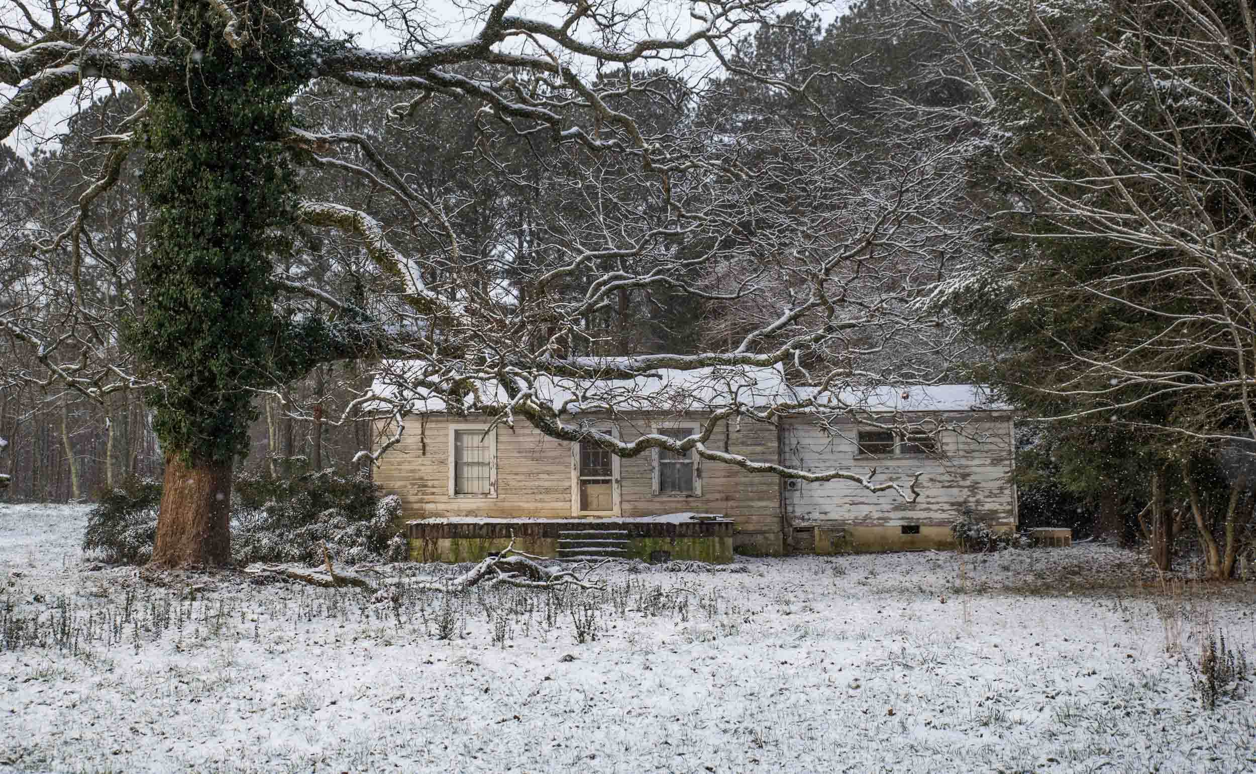 Sunlight shines on a house during a light snow fall, Saturday, Jan. 23, 2016, in Woodstock, Ga.