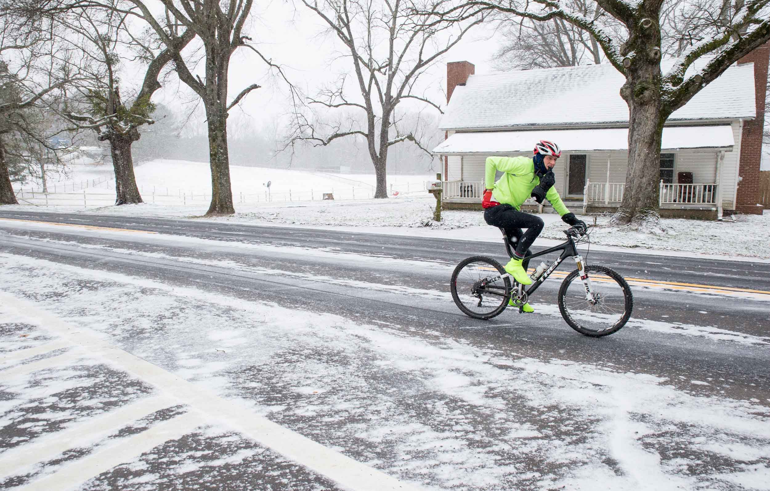 A cyclist rides on an ice covered street during a light snow fall, Saturday, Jan. 23, 2016, in Woodstock, Ga.